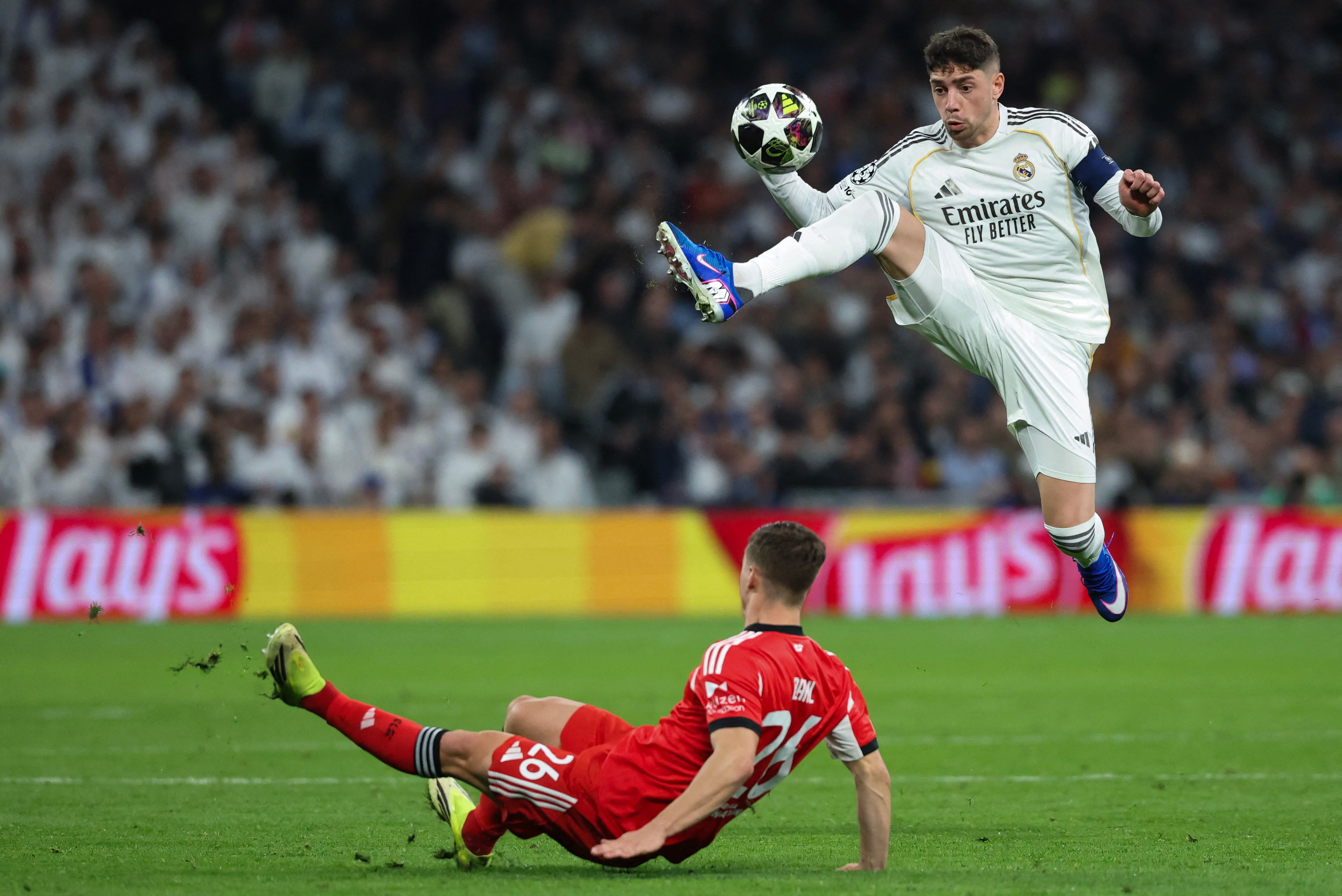 El volante uruguayo del Real Madrid Fede Valverde controla el balón ante el sueco del Benfica Samuel Dahl durante el partido por la Champions en el Santiago Bernabéu.