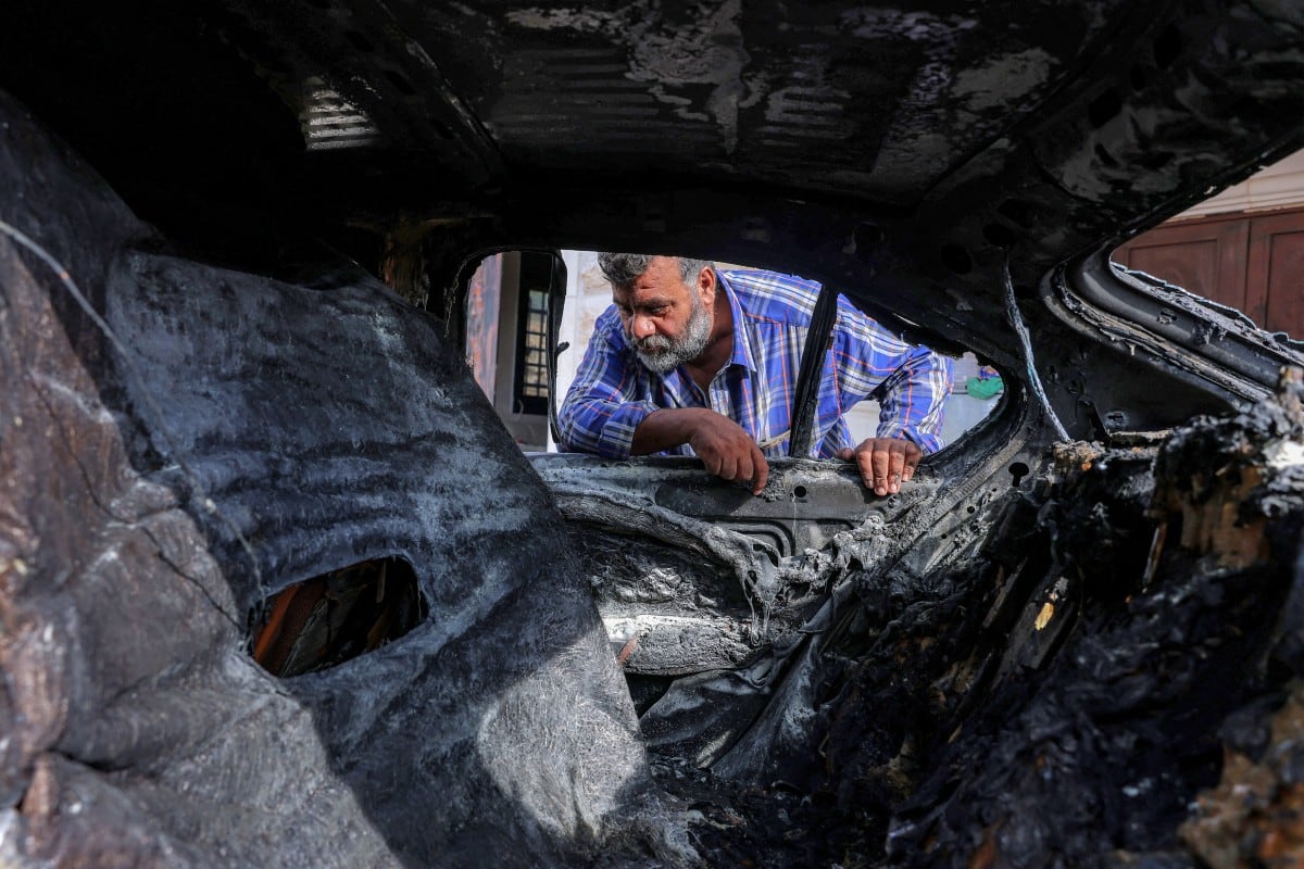 Un hombre palestino inspecciona uno de varios vehículos destruidos tras un ataque de colonos israelíes, en la aldea palestina de al-Mughayyir, cerca de Ramala, en la Cisjordania ocupada por Israel.