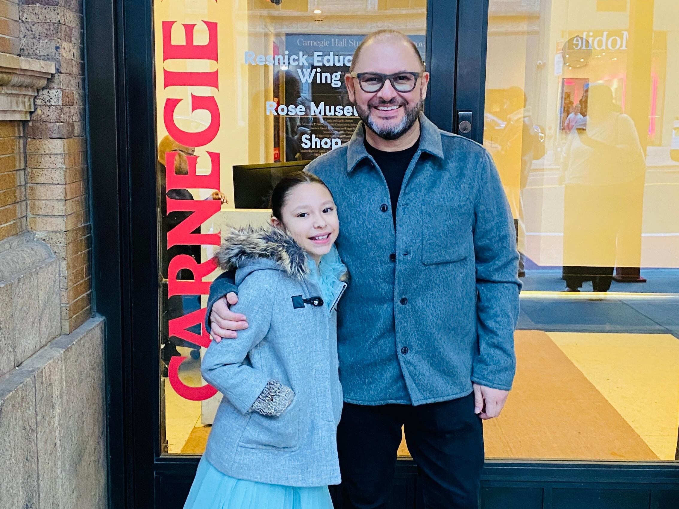 Niña posa junto a su padre en una entrada del Carnegie Hall