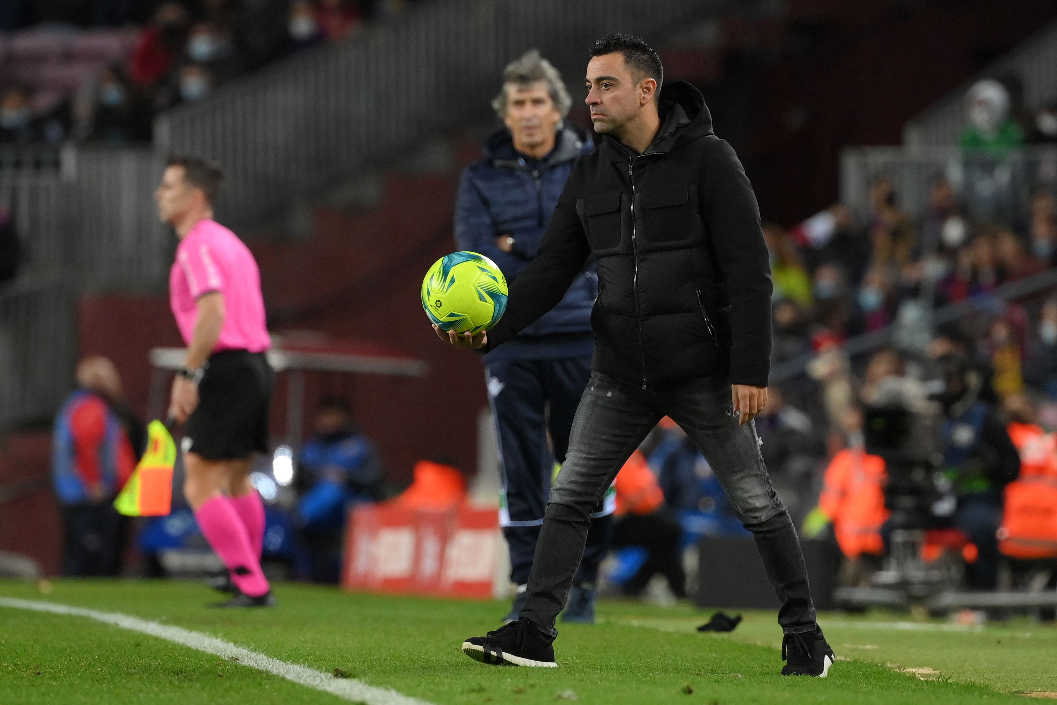 El técnico Xavi Hernández toma el balón durante la derrota del Barcelona ante el Real Betis. AFP
