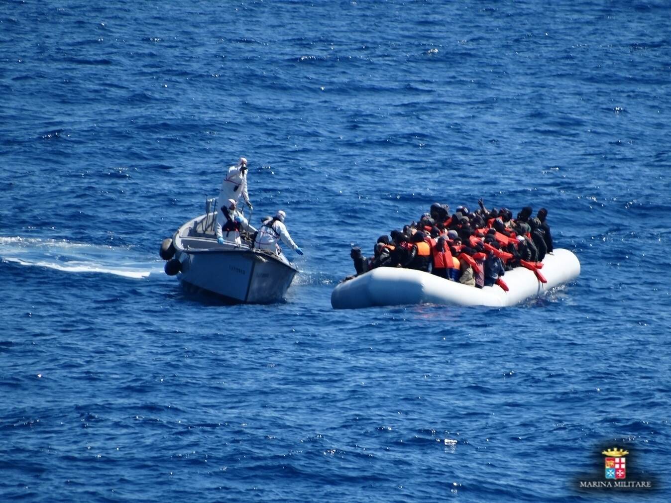 Personal naval italiano se acerca a una lancha de goma llena de migrantes en el Mediterraneo, este viernes.