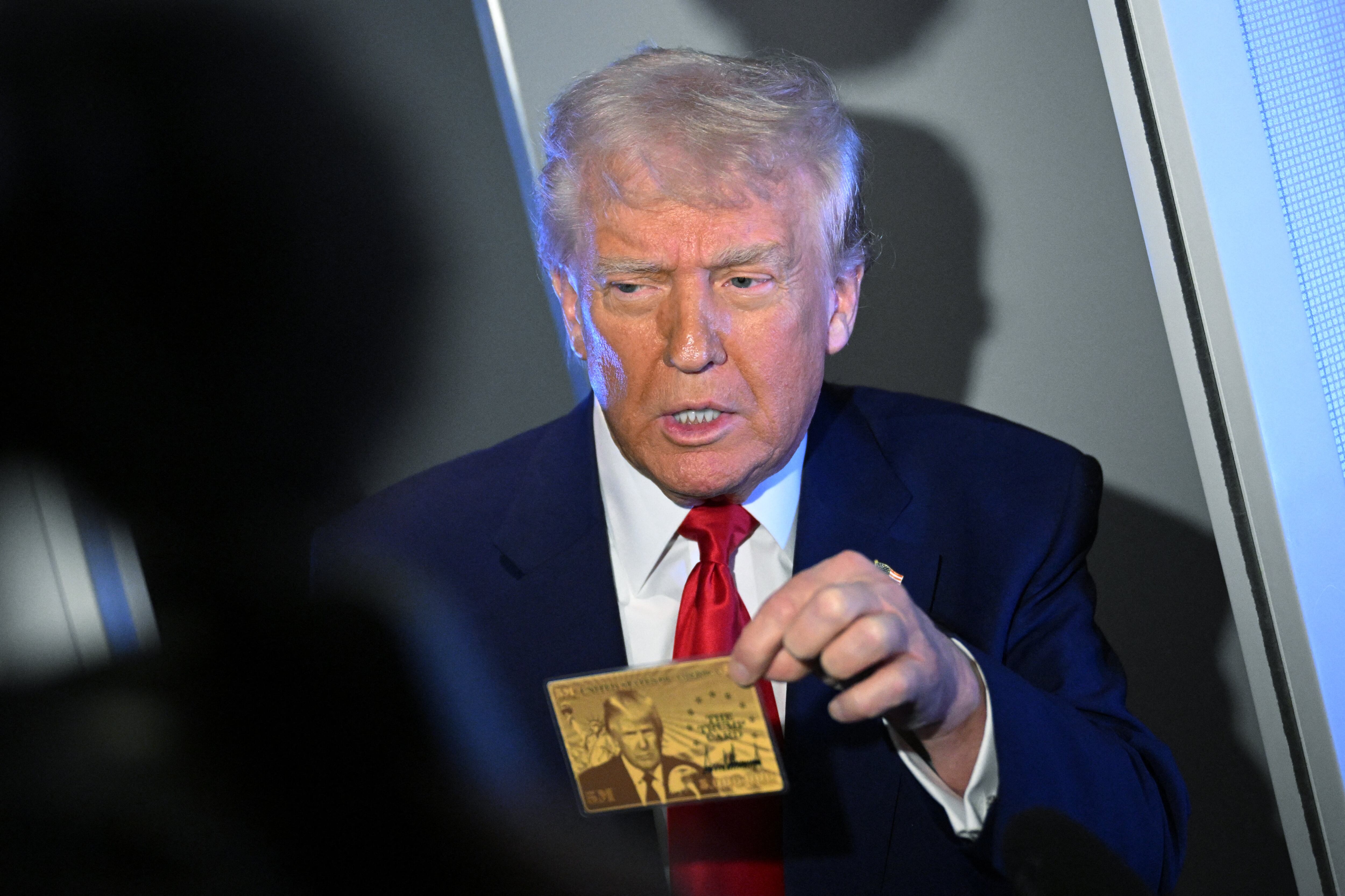 US President Donald Trump holds the $5 million dollar Gold Card as he speaks to reporters while in flight on board Air Force One, en route to Miami, Florida on April 3, 2025. Trump is travelling to the Trump National Doral Golf Club before going to his Mar-a-Lago Resort. (Photo by MANDEL NGAN / AFP)