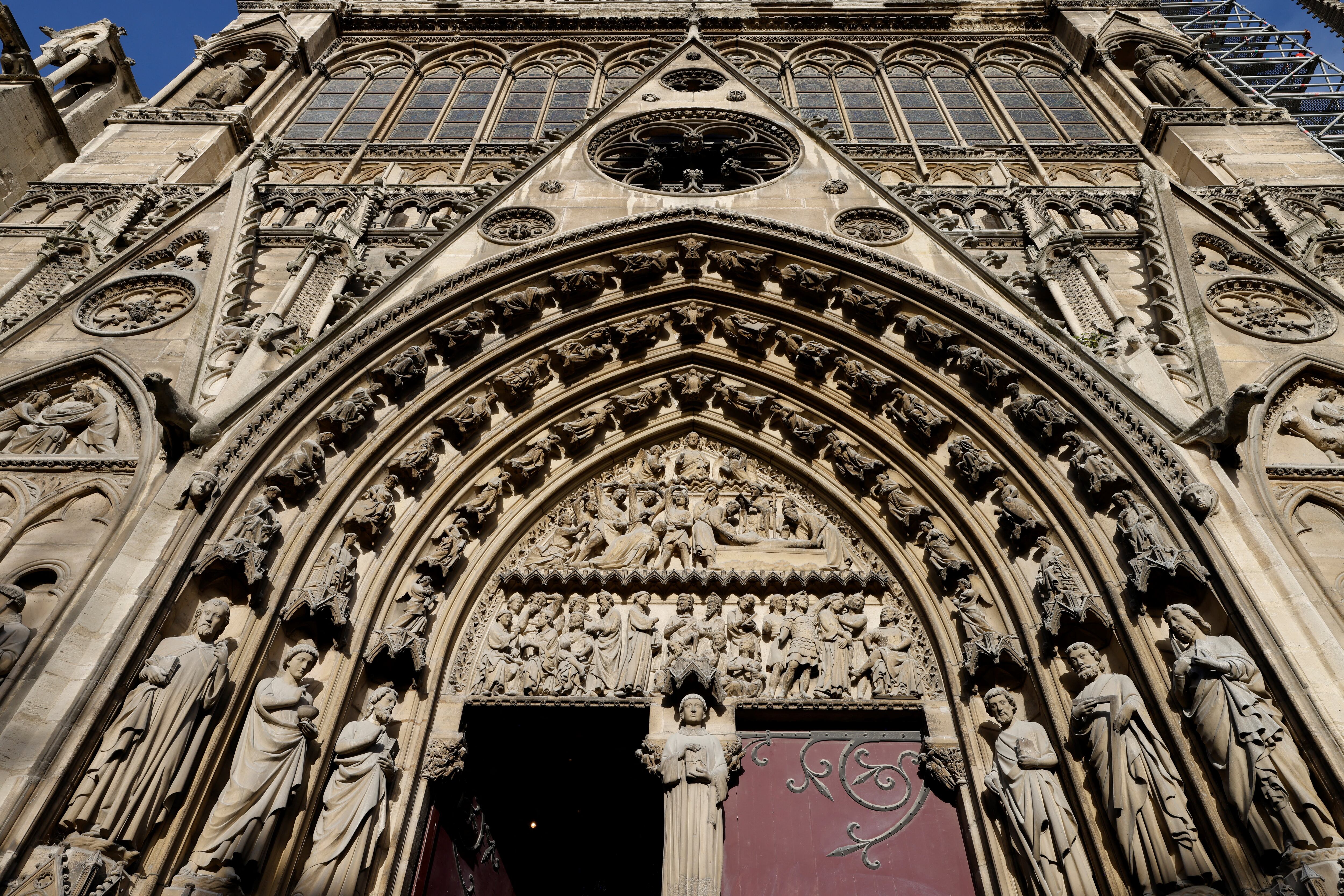 Detalle de la fachada gótica restaurada de la catedral de Notre Dame de París, con esculturas y arcos característicos.