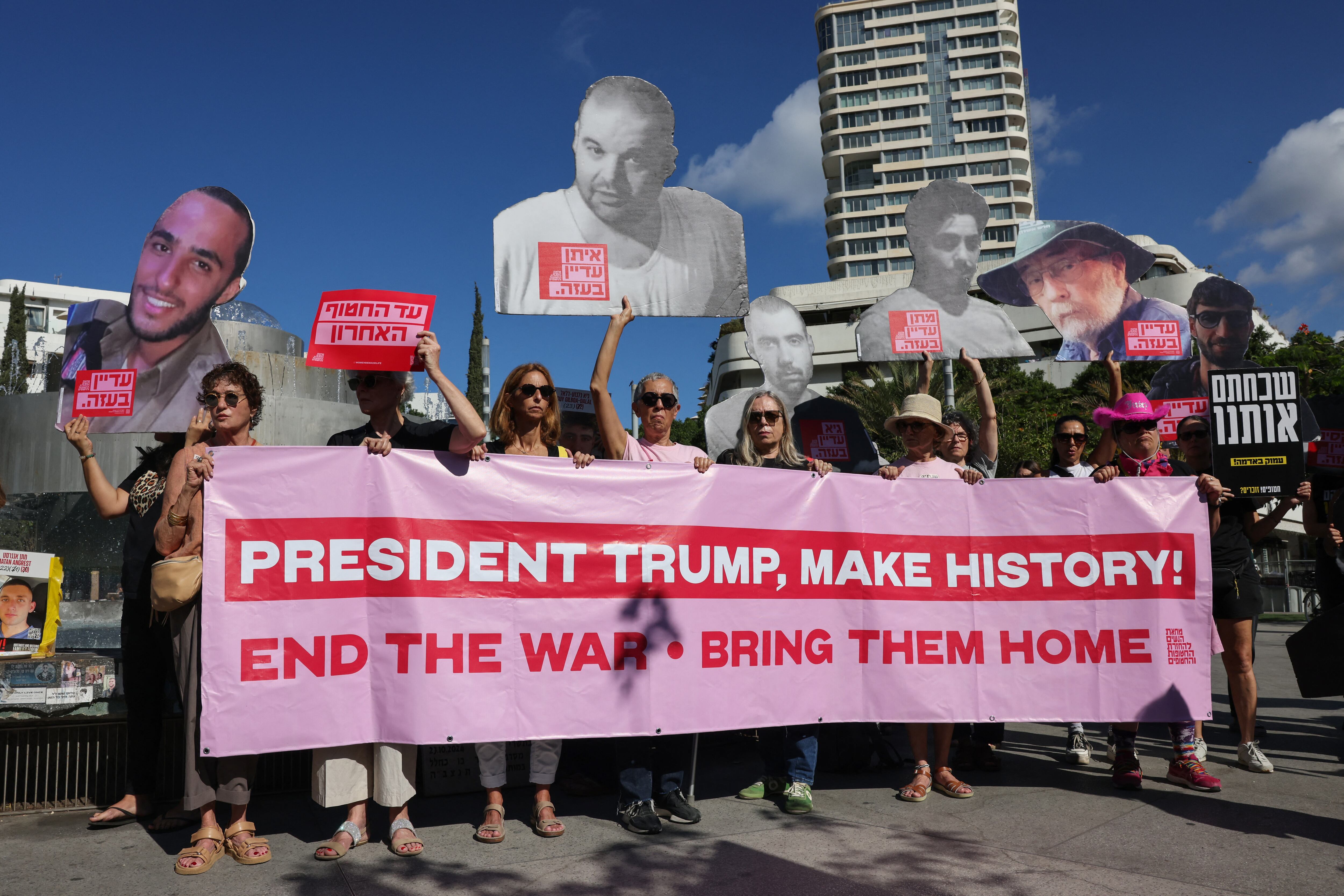 Personas alzan una pancarta que dice, "Presidente Trump, haga la historia! Acabe con la guerra, traigamos a casa." También alzan retratos de israelíes secuestrados en la Franja de Gaza desde 2023, durante una manifestación en Tel Aviv para conmemorar el segundo aniversario de los ataques de militantes palestinos, el 7 de octubre de 2025.