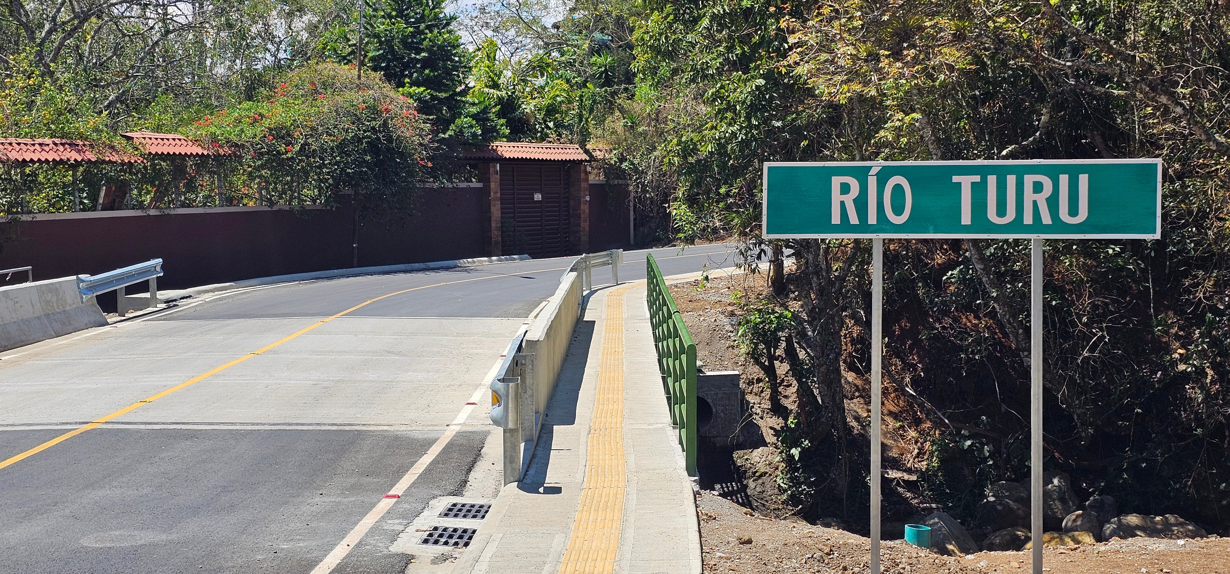 Nuevo puente en Calle Gildo sobre río Turú reemplaza paso deteriorado. Tiene dos carriles, aceras peatonales y mayor capacidad hidráulica para tránsito segur