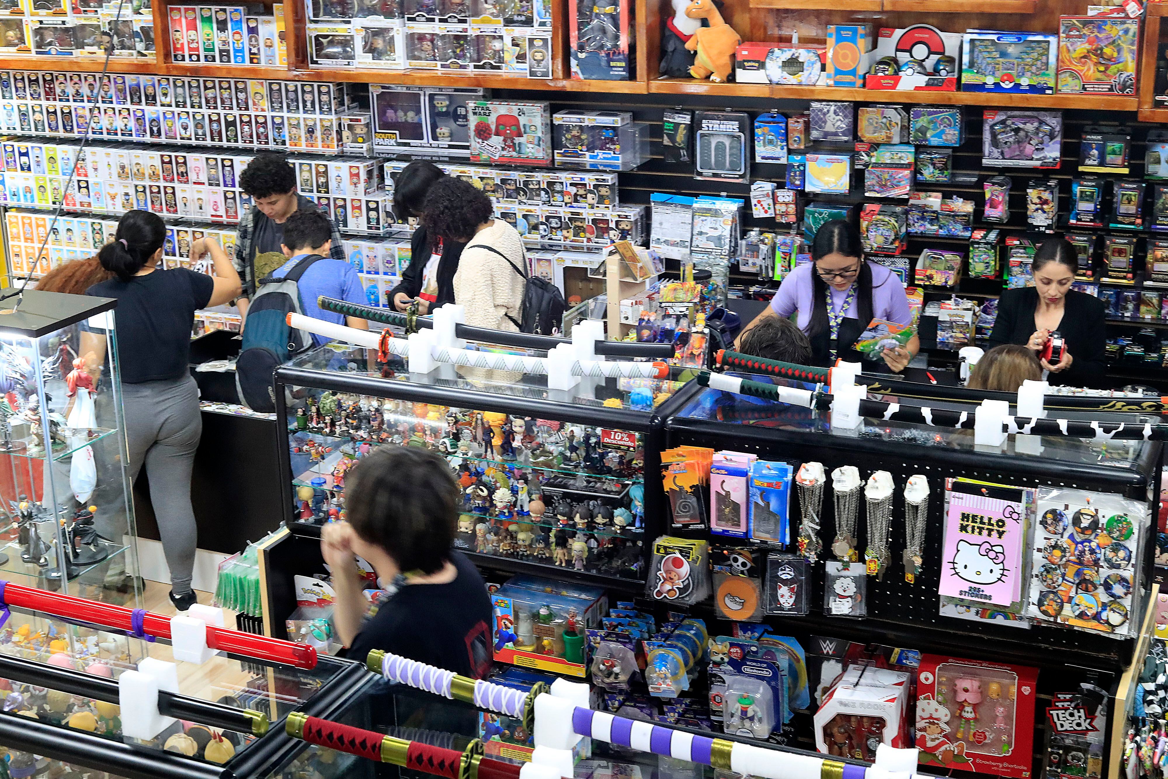 Clientes interactúan en una tienda de coleccionables en Costa Rica, rodeados de figuras de acción, espadas decorativas y juguetes, representando la actividad del sector comercio en el país.