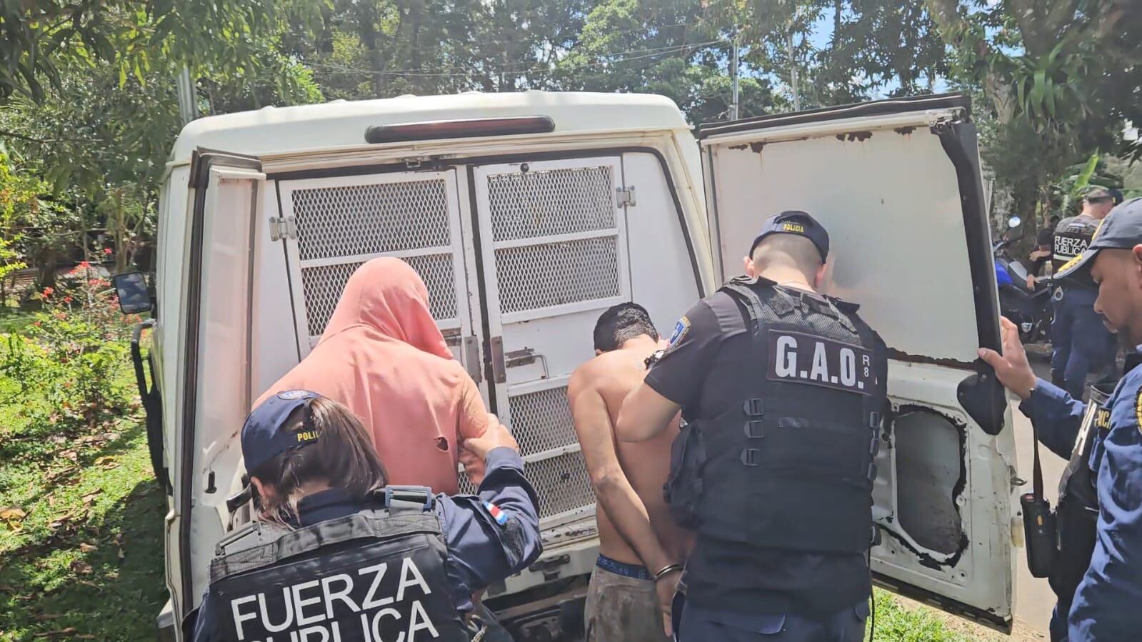 Dos tipos de espaldas siendo arrestados por la policía.