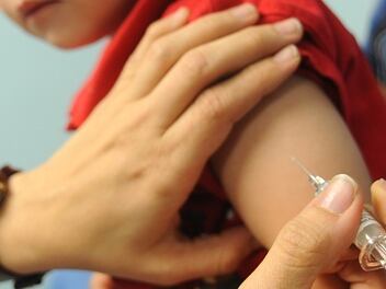 El brazo de un niño recibiendo una vacuna de manos de un adulto.