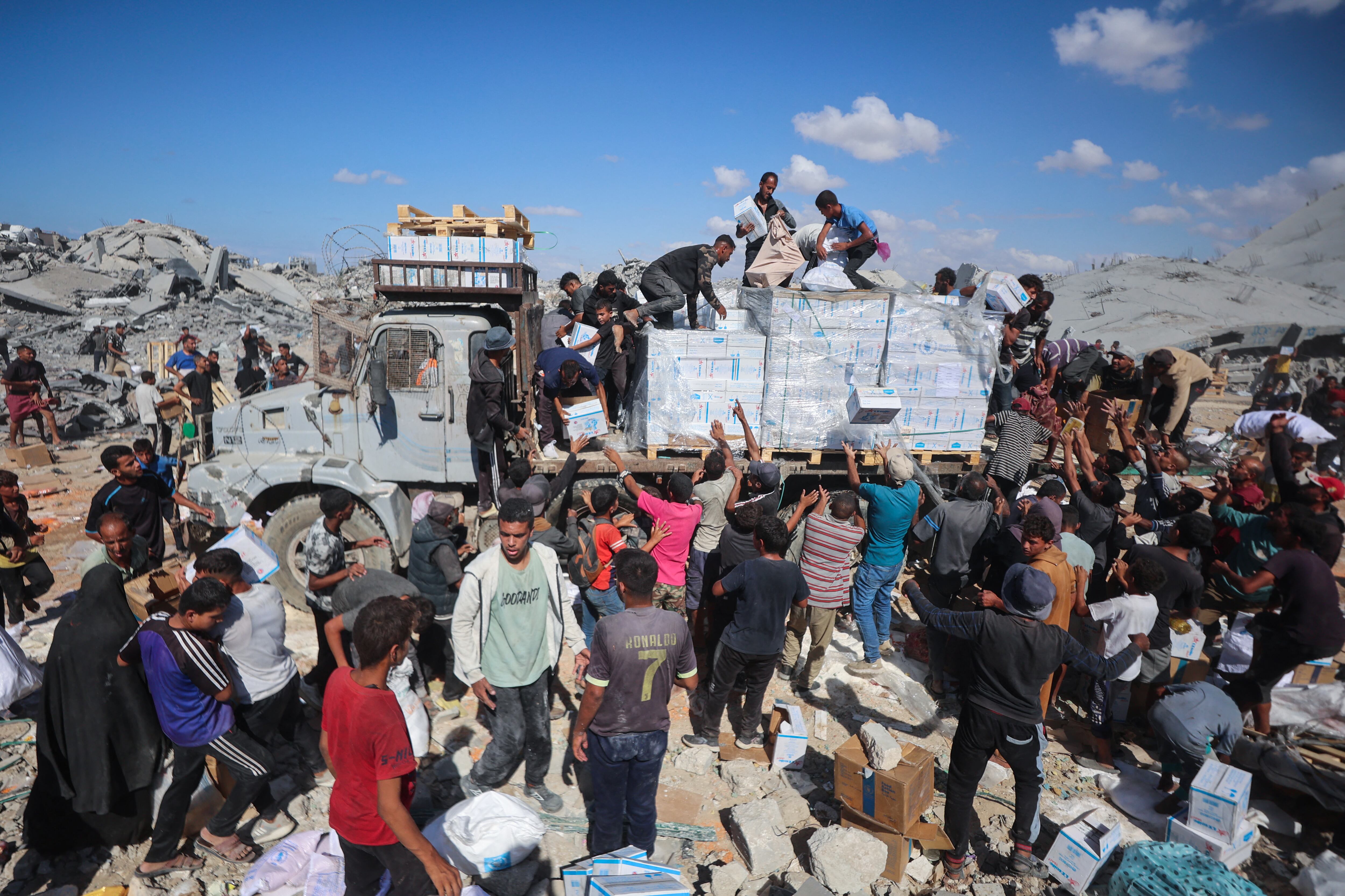 Palestinos reciben paquetes de alimentos tras la entrada de camiones de ayuda desde el cruce de Karem Abu Salem, en Khan Yunis, al sur de la Franja de Gaza, este 12 de octubre, mientras se mantiene el alto el fuego entre Israel y las facciones palestinas en el territorio asediado. Fotografía: