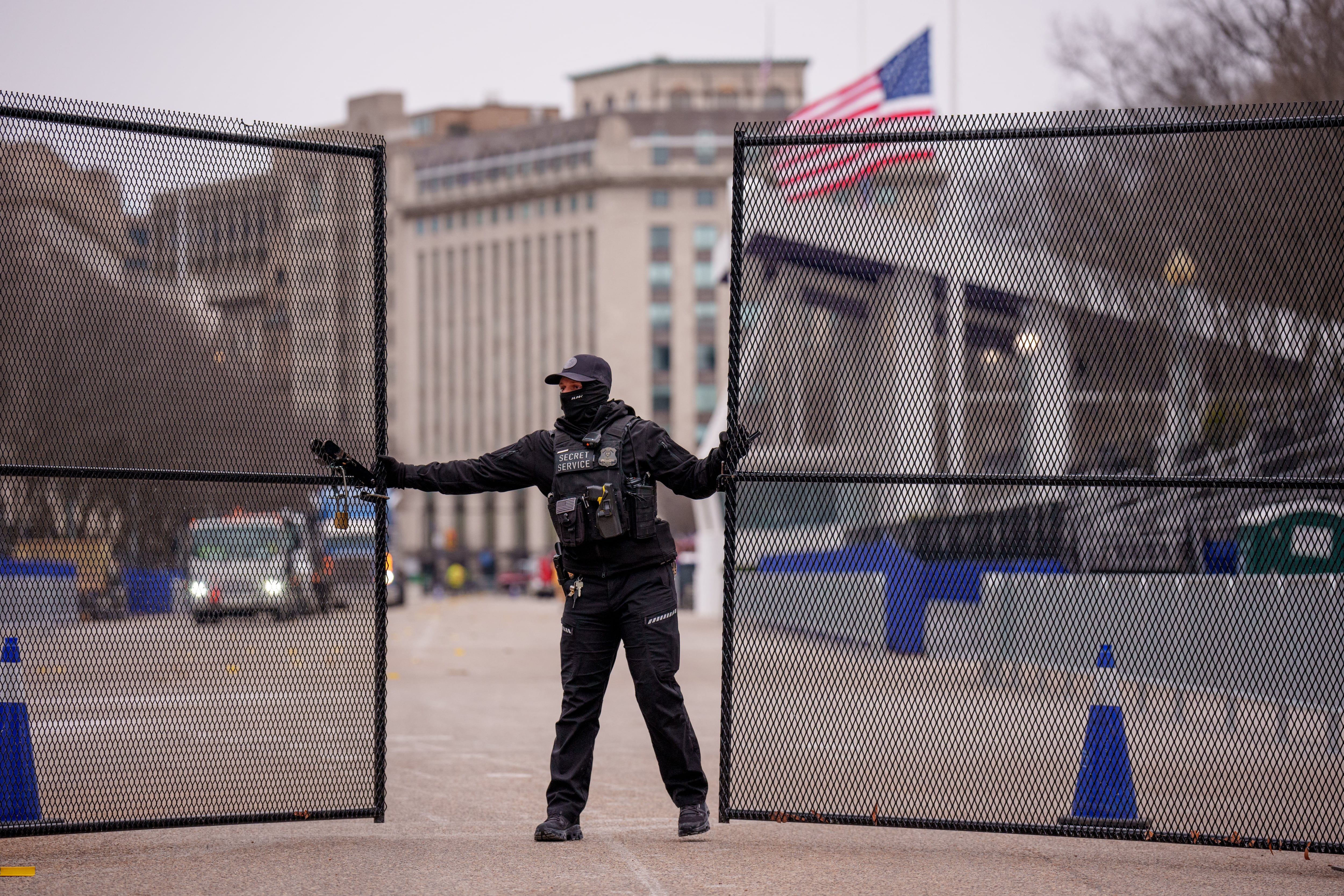 Un miembro del Servicio Secreto de los Estados Unidos cierra una puerta de seguridad cerca del puesto de revisión del desfile de investidura presidencial en Pennsylvania Avenue, en el lado norte de la Casa Blanca. Las autoridades han instalado un récord de 48 kilómetros de cercas antiescalada.