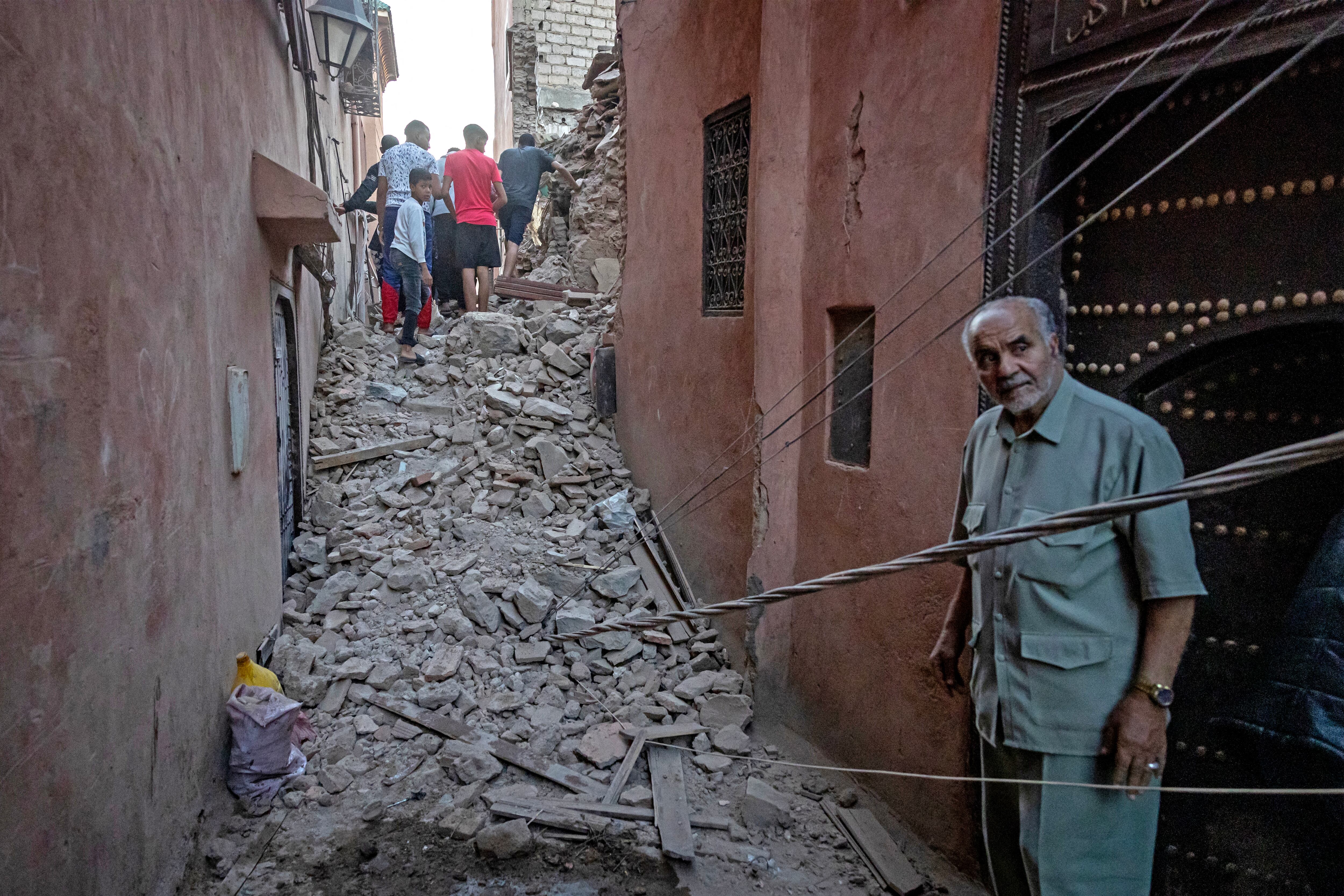 Un hombre observa mientras los residentes navegan entre los escombros en la antigua ciudad de Marrakech, dañada por el terremoto,