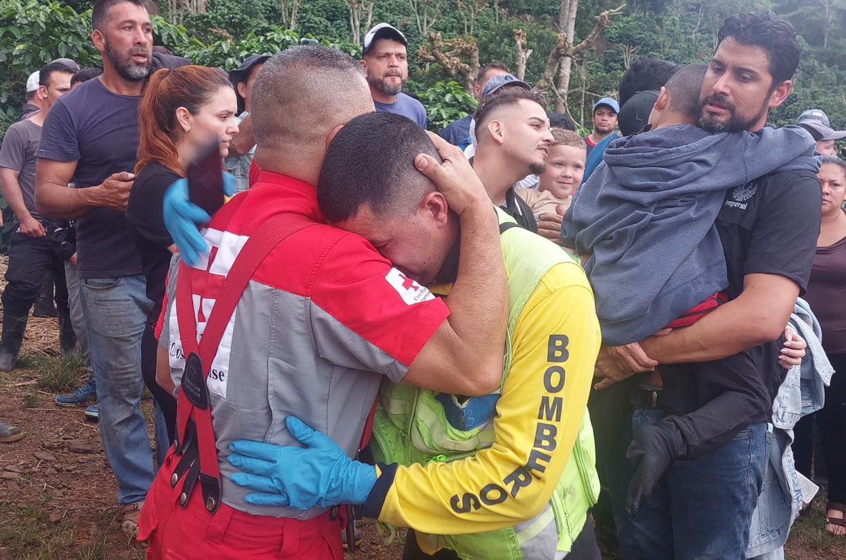 El bombero que le midió el ritmo cardiaco a Matheo se abraza con otro cruzrojista que atendió el rescate en Pérez Zeledón. Atrás el papá y el niño al fin reunidos. Una imagen y mil emociones.