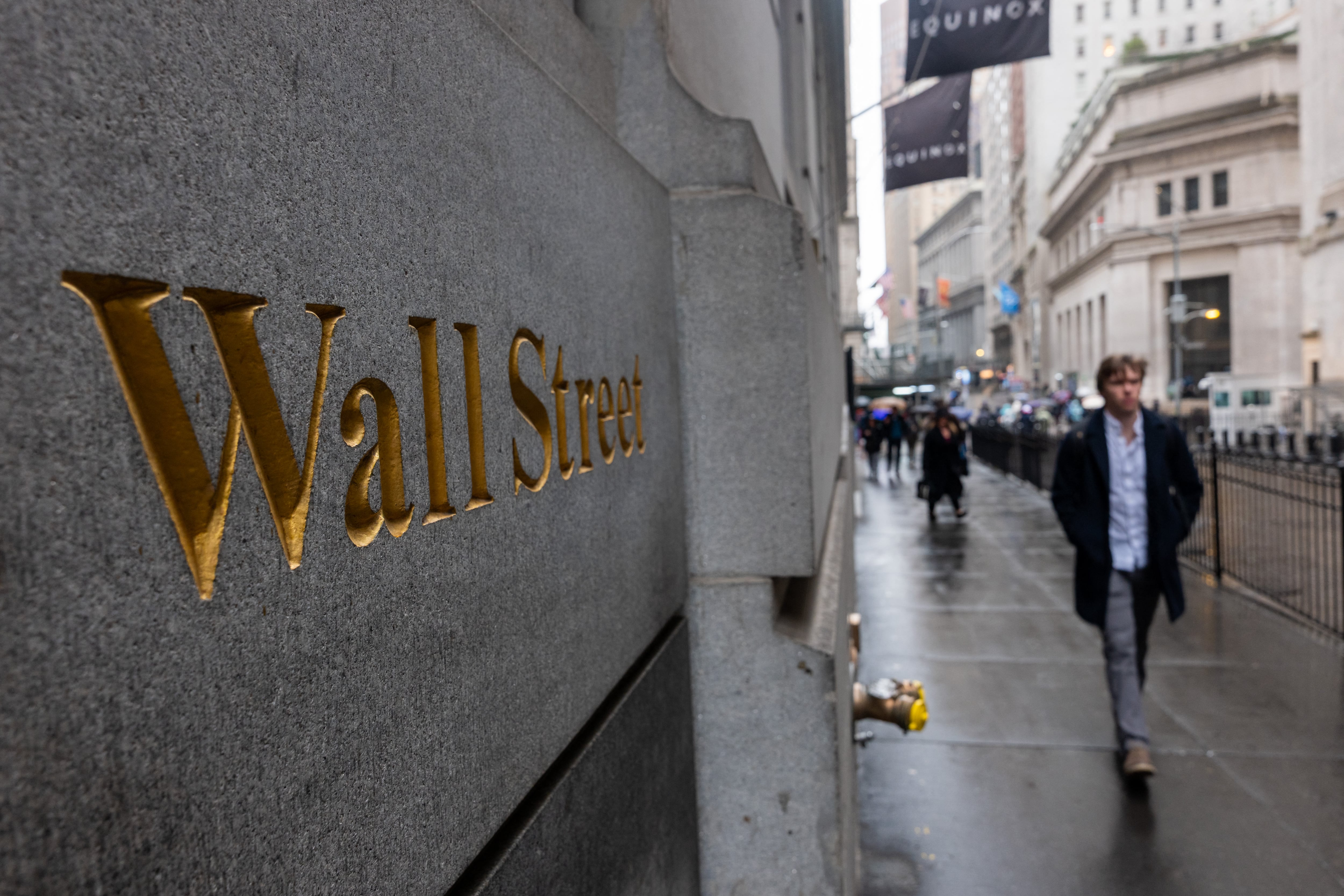 Rótulo de Wall Street en una pared y una persona caminando