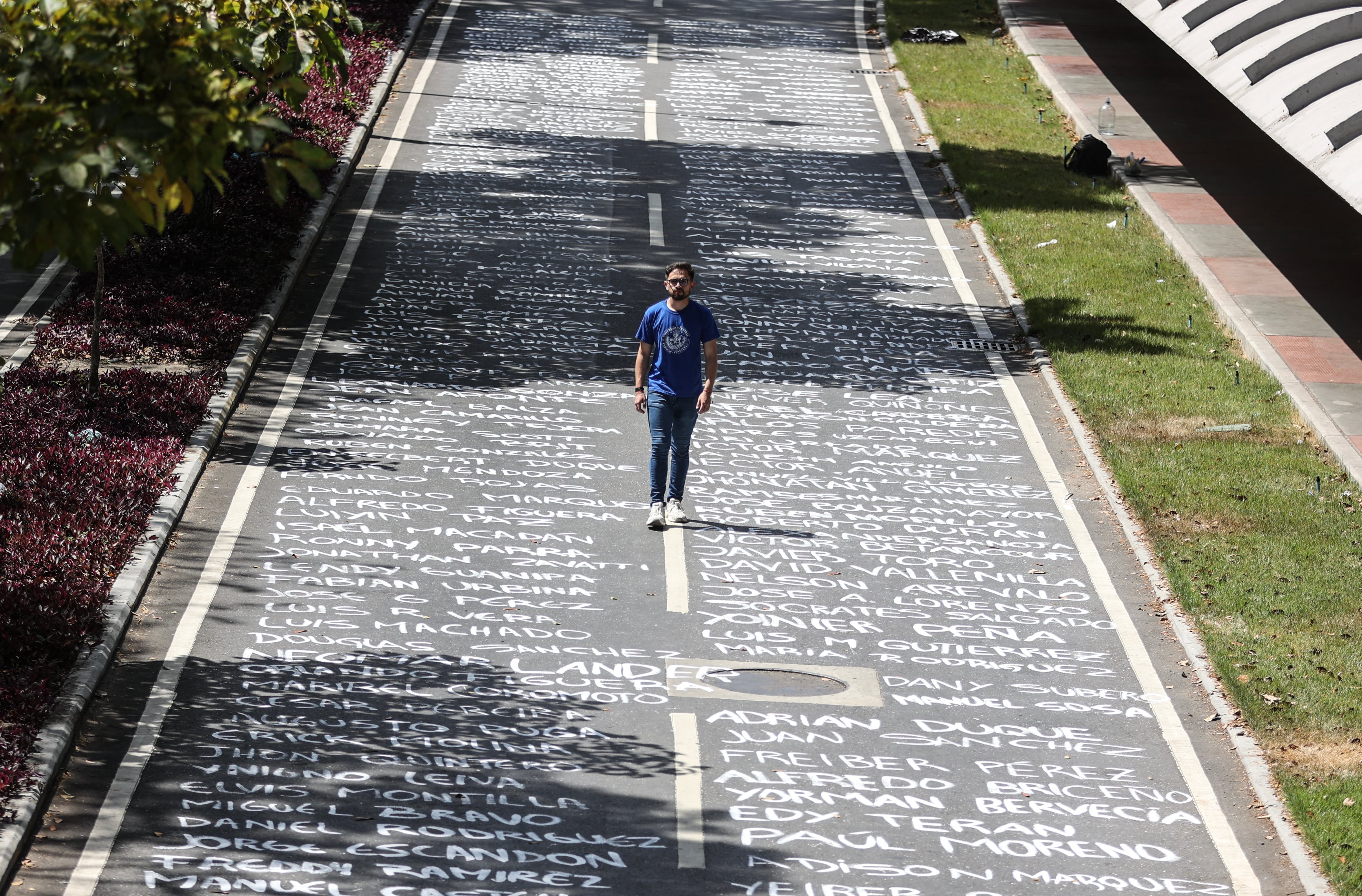 A student at the Central University of Venezuela walks over names of missing students painted on the floor of the university entrance in celebration of Venezuelan Youth Day in Caracas on February 12, 2025. (Photo by Pedro MATTEY / AFP)