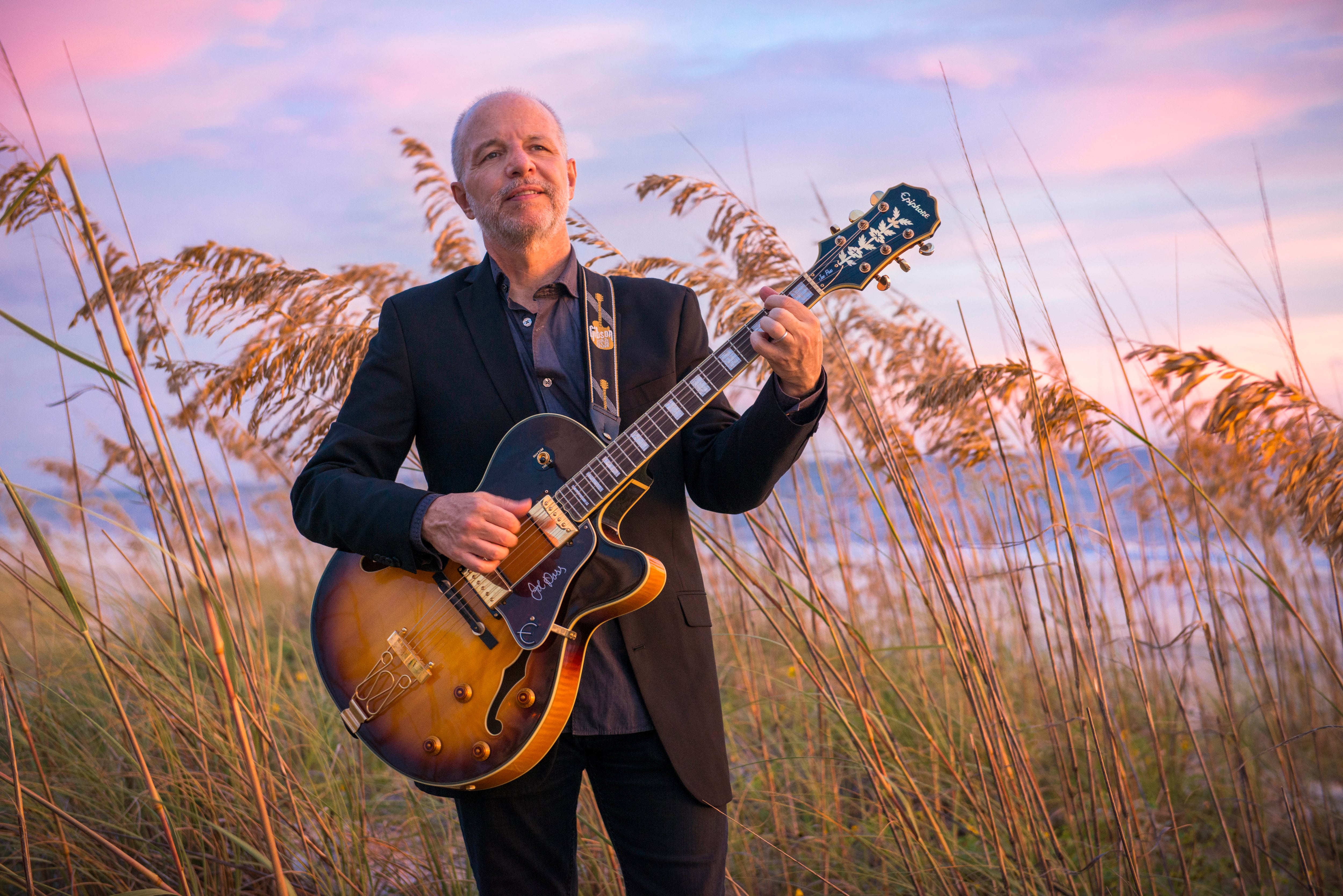 Foto de Alberto Plaza tocando su guitarra en un jardín.