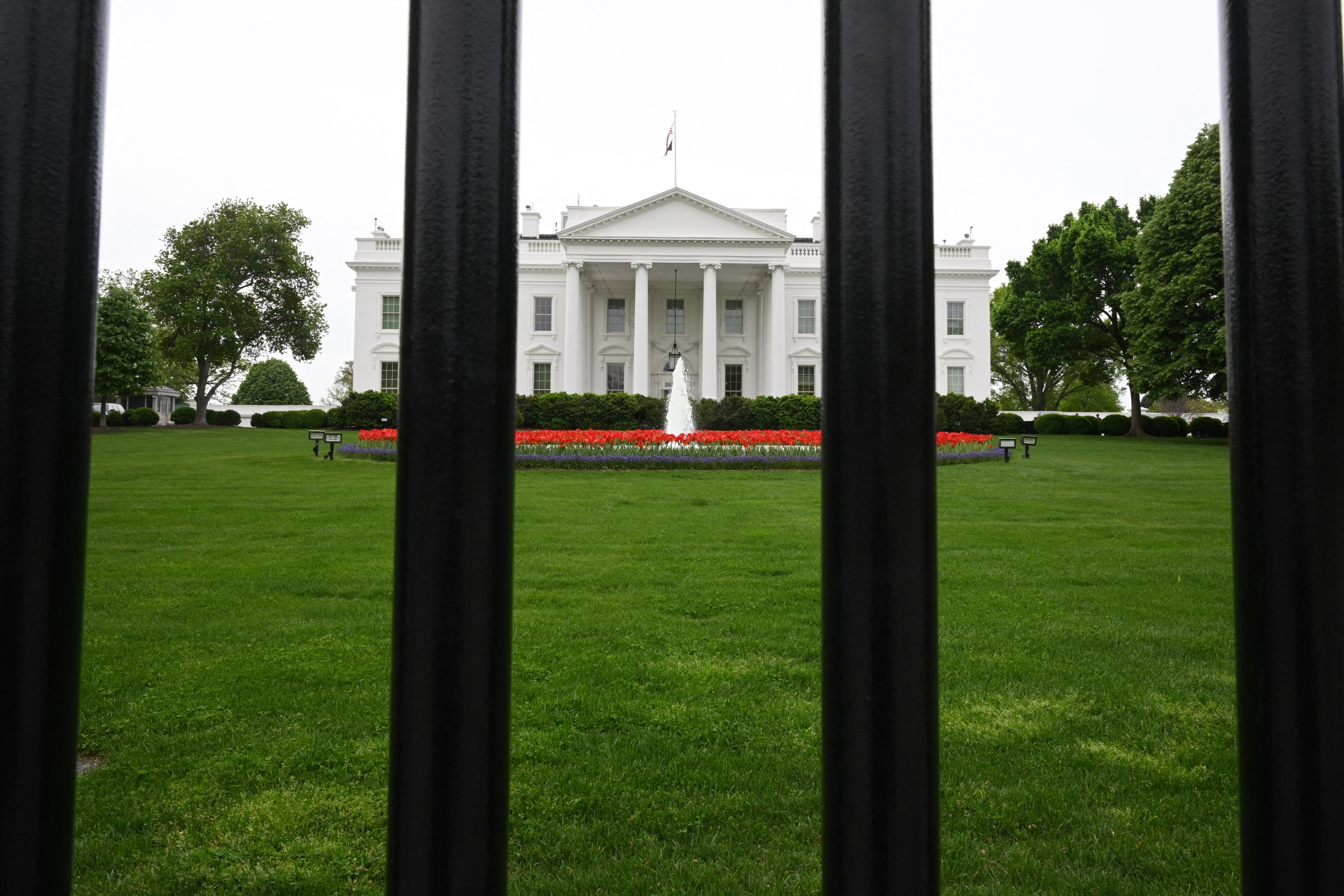 The White House is seen behind bars from a fence in Washington, DC on April 19, 2025. (Photo by MANDEL NGAN / AFP)