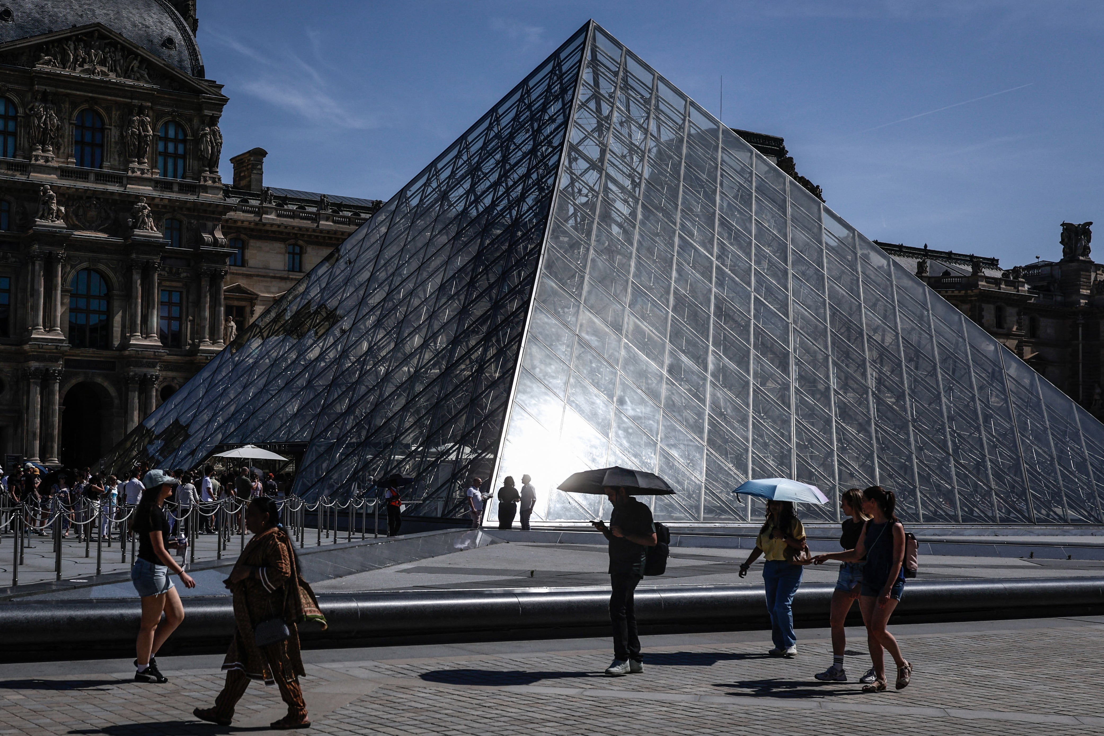 Turistas caminan frente al Museo del Louvre, en París, este 28 de mayo de 2026, mientras una ola de calor afecta a Francia. El servicio meteorológico Météo-France declaró alerta amarilla en la capital ante las altas temperaturas, que podrían alcanzar los 35 °C en la región. (Foto: Stephane de Sakutin / AFP)
