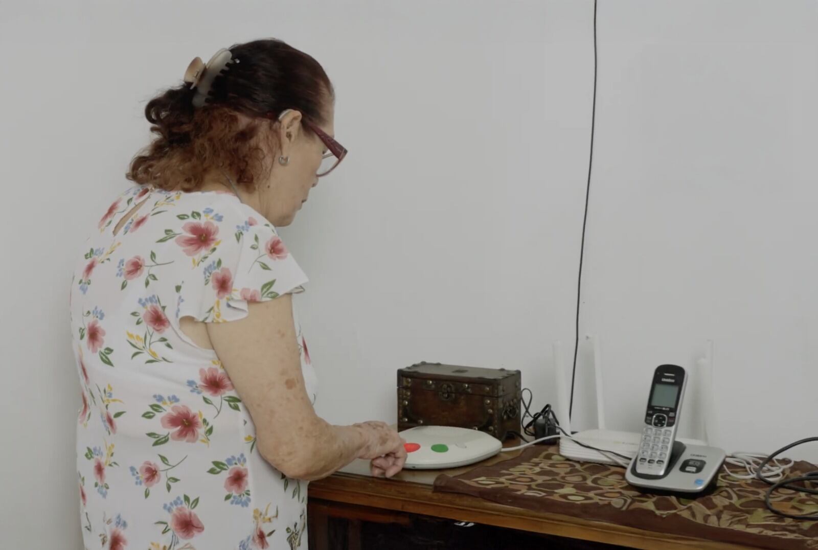 Una adullta mayor, de espaldas, utiliza servicio de teleasistencia.