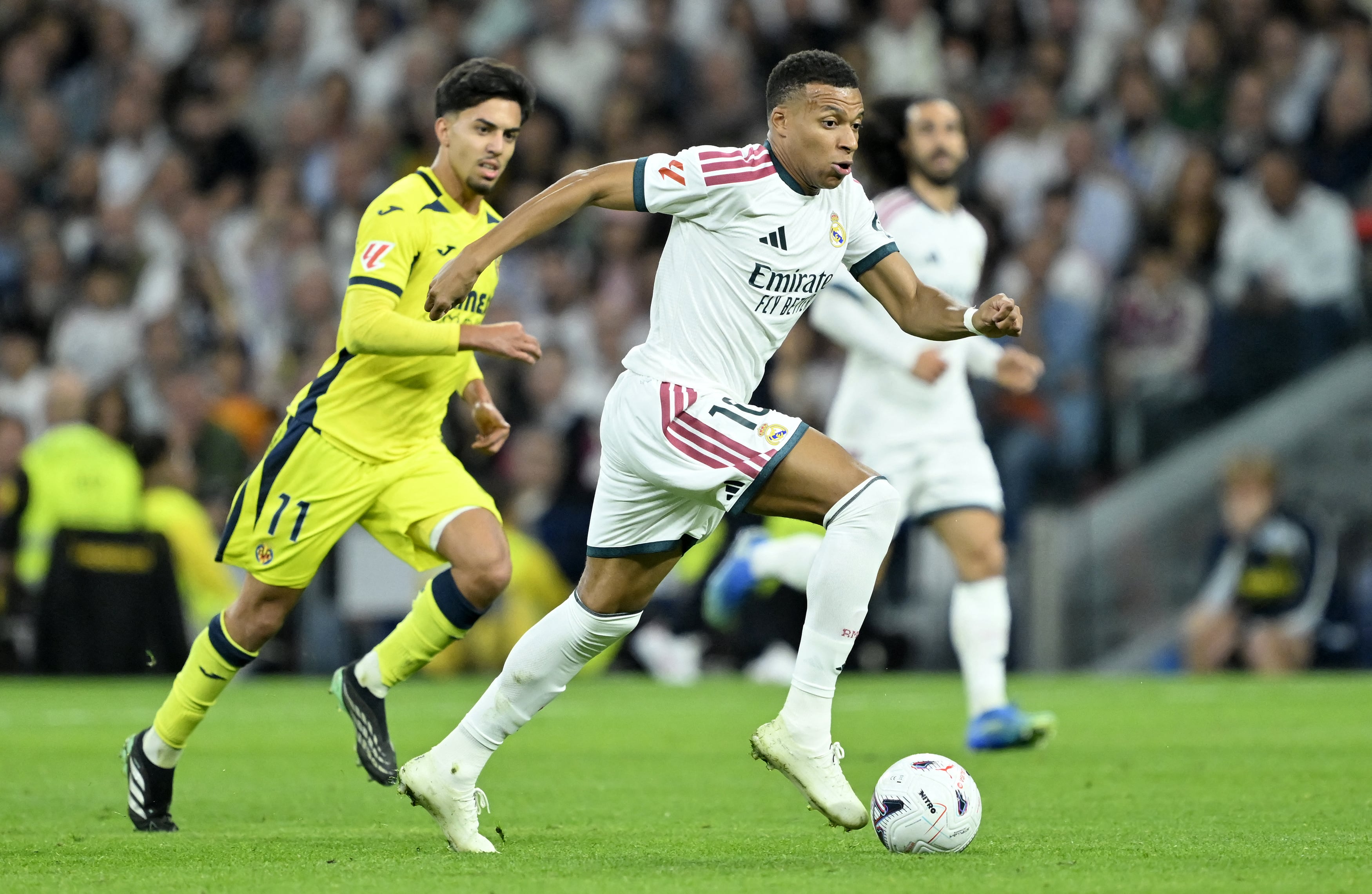 El delantero Kylian Mbappé, del Real Madrid, conduce el balón ante la marca de Ilias Chakkour, del Villarreal, en este duelo de la Liga Española en el estadio Santiago Bernabéu.