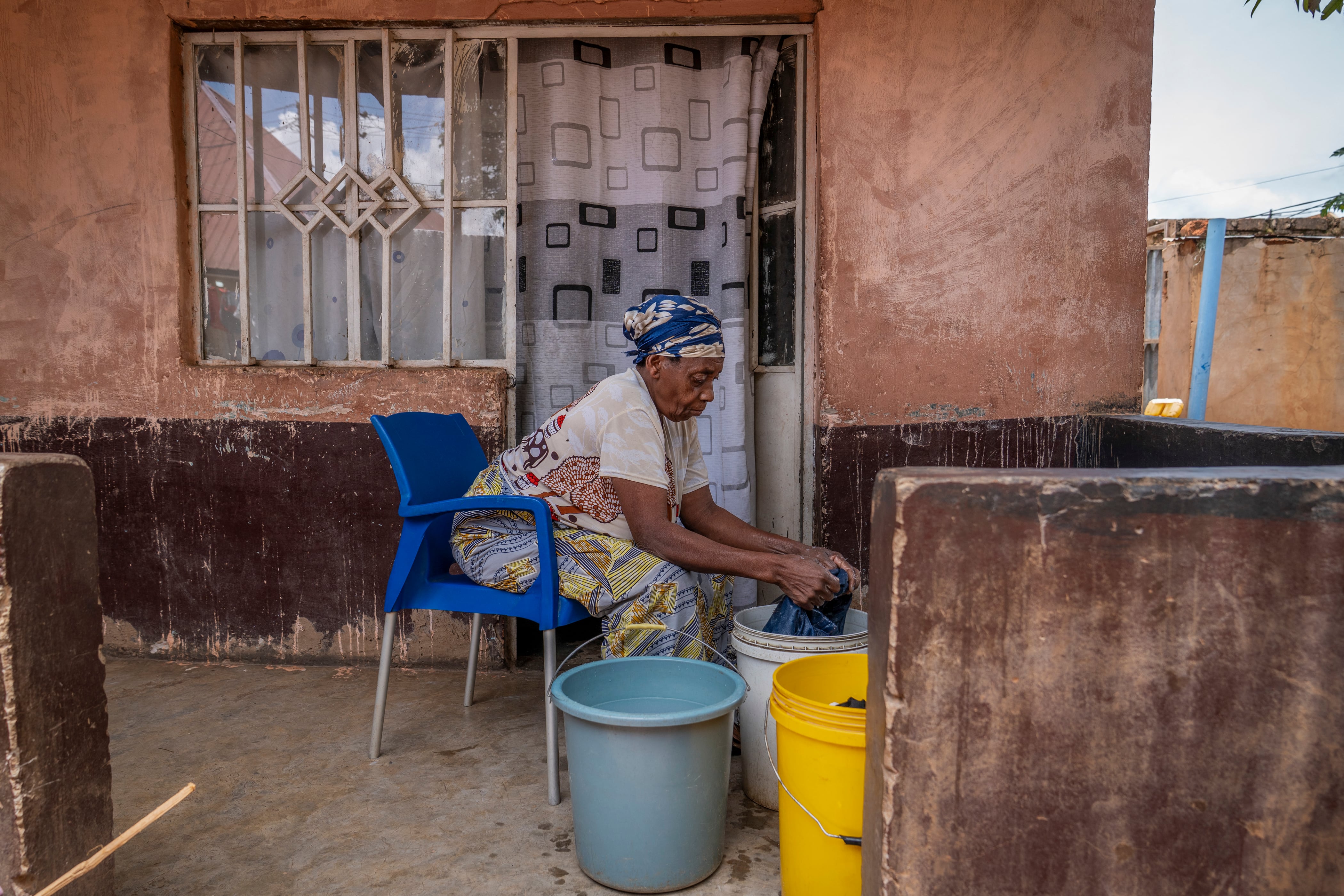 Hortance Kiluba lava la ropa a mano en su casa, en el distrito de Kamitete, Lubumbashi, el 24 de noviembre de 2025. Su campo reseco está invadido por los escombros arrastrados por las aguas contaminadas, y la niña que lleva en brazos está cubierta de llagas: en Lubumbashi, la capital minera de la República Democrática del Congo (RDC), miles de congoleños afirman ser víctimas de los residuos tóxicos de la industria minera.
