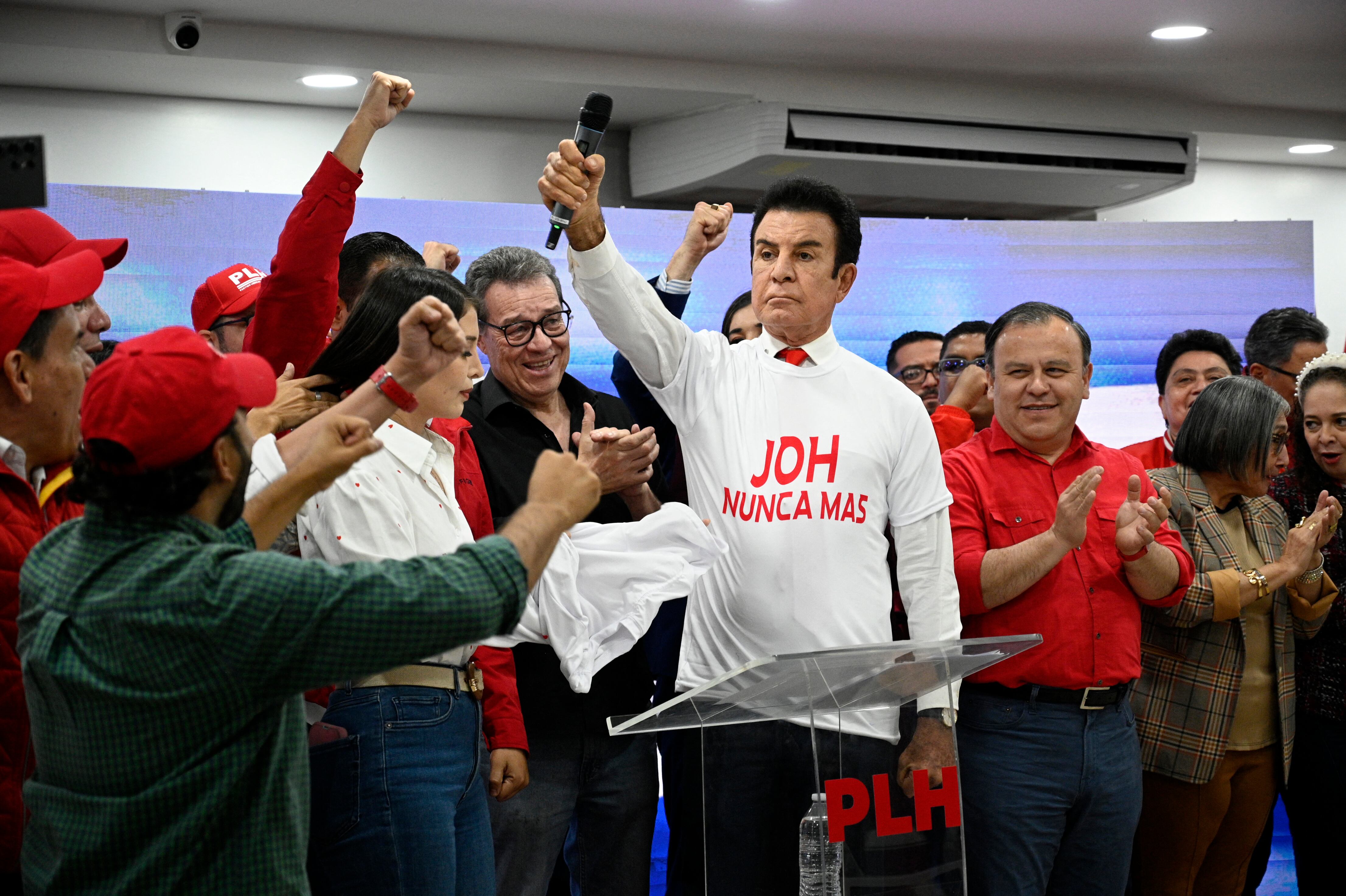 Salvador Nasralla (C), candidato presidencial hondureño por el opositor Partido Liberal, viste una camiseta con la leyenda "JOH Nunca Más", en referencia al expresidente Juan Orlando Hernández, durante una conferencia de prensa en Tegucigalpa el 28 de noviembre de 2025. El presidente de Estados Unidos, Donald Trump, anunció el viernes que indultará al expresidente hondureño Juan Orlando Hernández, quien fue declarado culpable de narcotráfico y sentenciado a 45 años de prisión en Estados Unidos.