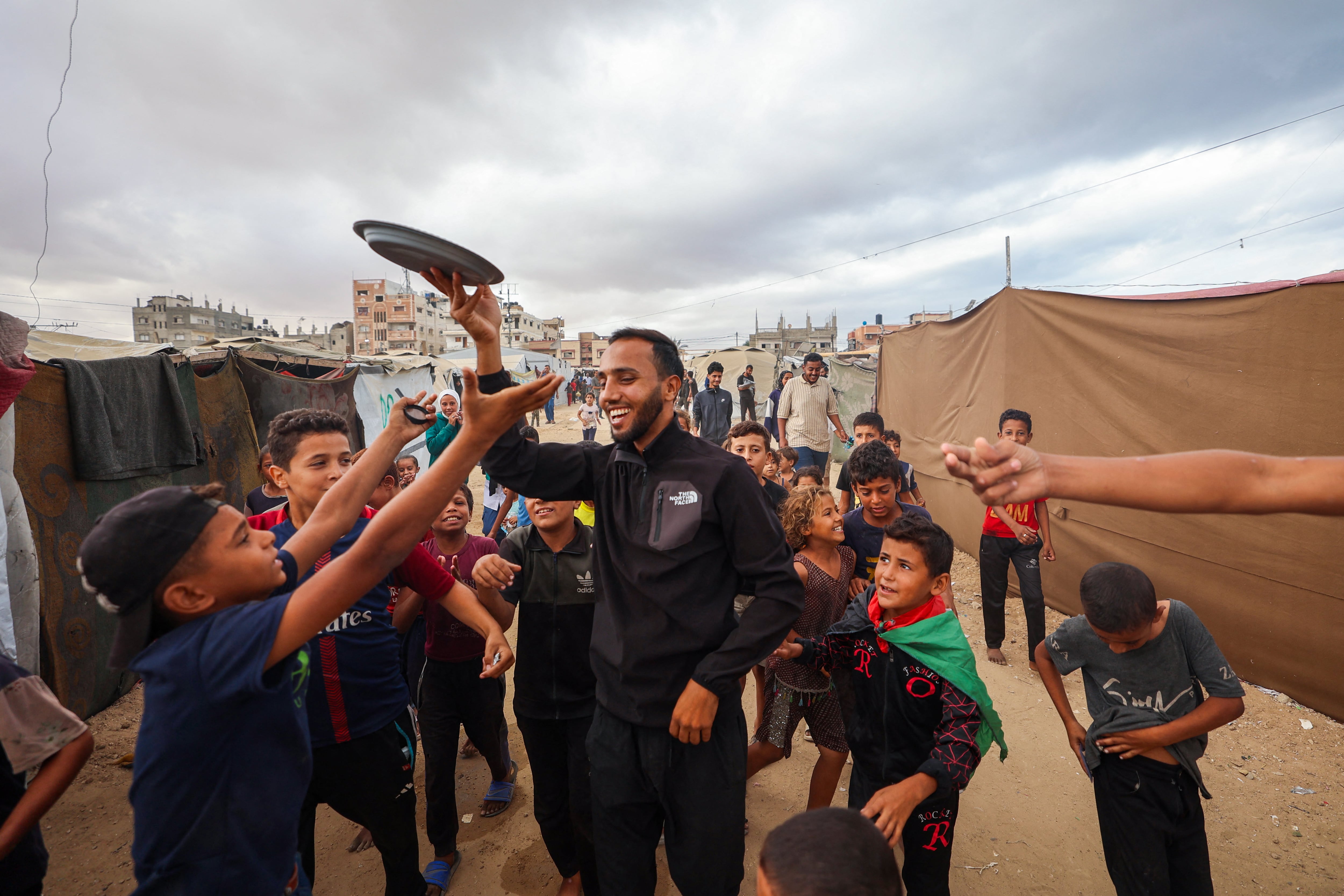 Un hombre distribuyó dulces en un campamento para palestinos desplazados en Nuseirat, en el centro de la Franja de Gaza, este 9 de octubre, tras la noticia de un nuevo acuerdo de alto el fuego en Gaza. Fotografía: