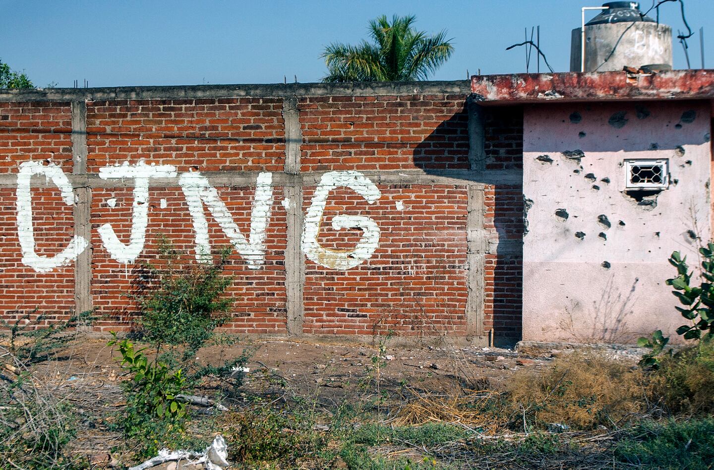 Vista de un muro acribillado a balazos con las iniciales del grupo criminal Cártel Jalisco Nueva Generación (CJNG) a la entrada de la comunidad de Aguililla, estado de Michoacán, México, el 23 de abril de 2021.