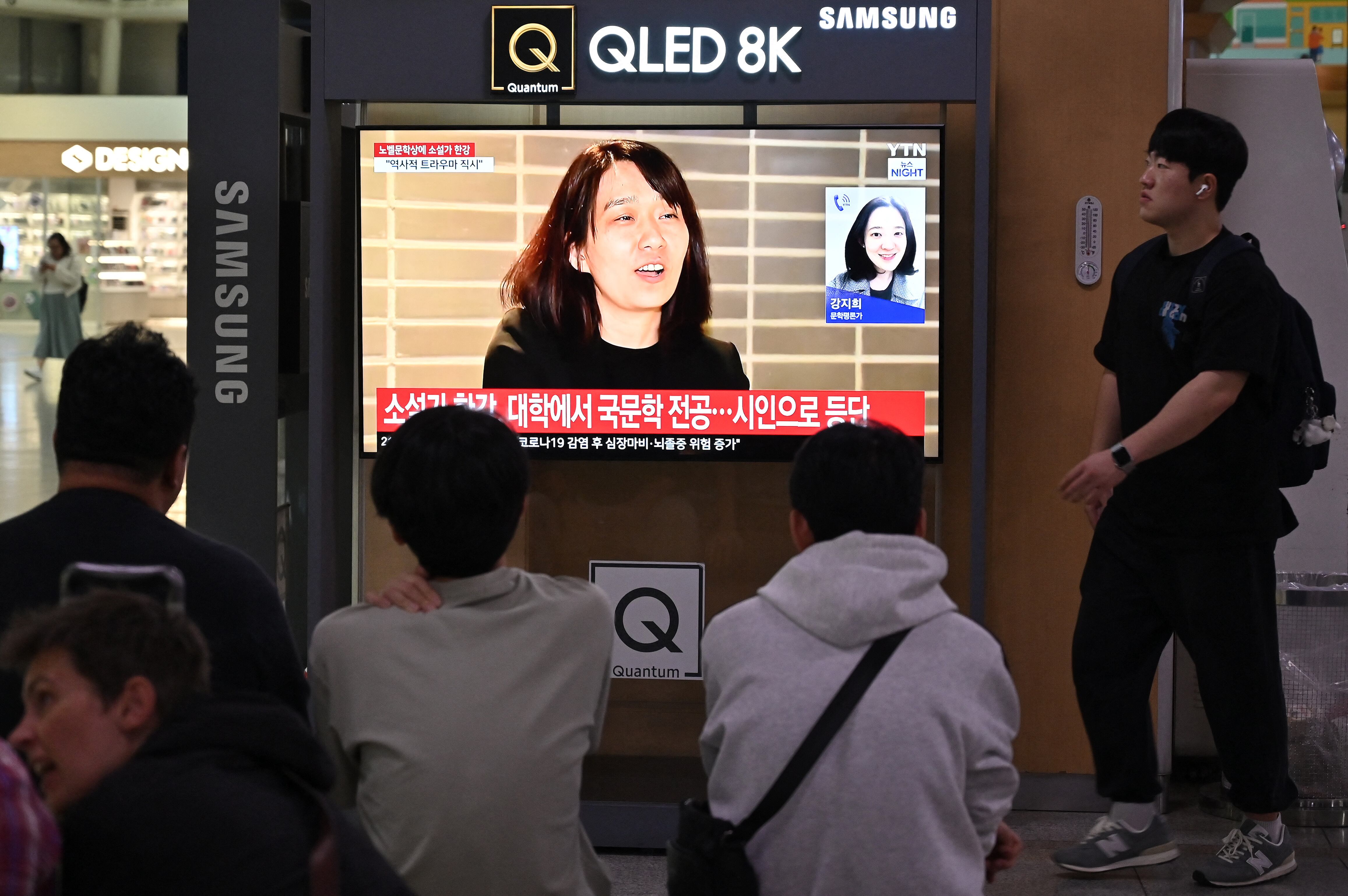 En Corea del Sur, las personas observan una transmisión de noticias con imágenes de archivo de la autora surcoreana Han Kang, en una estación de tren en Seúl, el 10 de octubre de 2024.