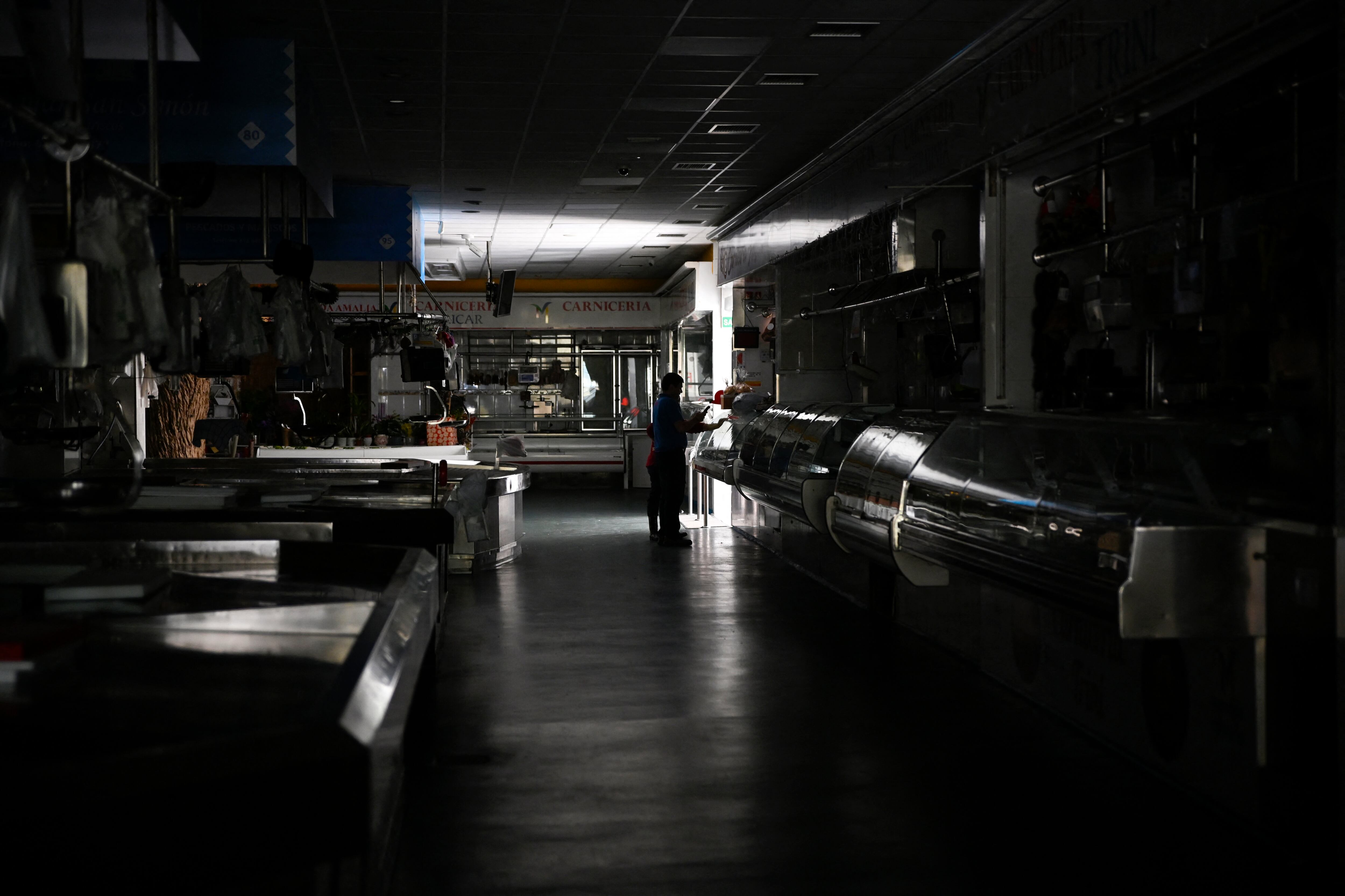 TOPSHOT - A man and a child walk through a local market during a massive power cut in Vigo, northwestern Spain, on April 28, 2025. A massive power cut a massive power cut affects the whole of the Iberian Peninsula and part of France on April 28, 2025, according to Portuguese electricity network operator REN. (Photo by MIGUEL RIOPA / AFP)