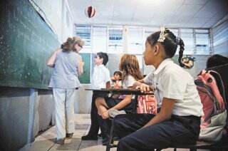 20/02/2013, hora: 09:30 a.m. Visita a la Escuela Finca La Caja, en La Carpio, donde los docentes esperan que el Ministerio de Educación Pública cumpla con la orden de la Sala Constitucional de darles un edificio que permita a los estudiantes recibir clases las horas suficientes y en instalaciones adecuadas. En la actualidad, la escuela debe hacer res turnos por día en tres edificios diferentes, ya que sólo cuentan con 16 aulas para una población de mil 800 estudiantes, quienes sólo reciben alrededor de cuatro horas de clases al día. En la foto, en el edificio conocido como EBI, que se le ha prestado a la escuela para impartir algunas clases, las condiciones no son las adecuadas, las aulas son pequeñas y tienen poca ventilación e iluminación. En la foto, la niña Guiselle Narváez lee en la pizarra la materia de la maestra de religión.