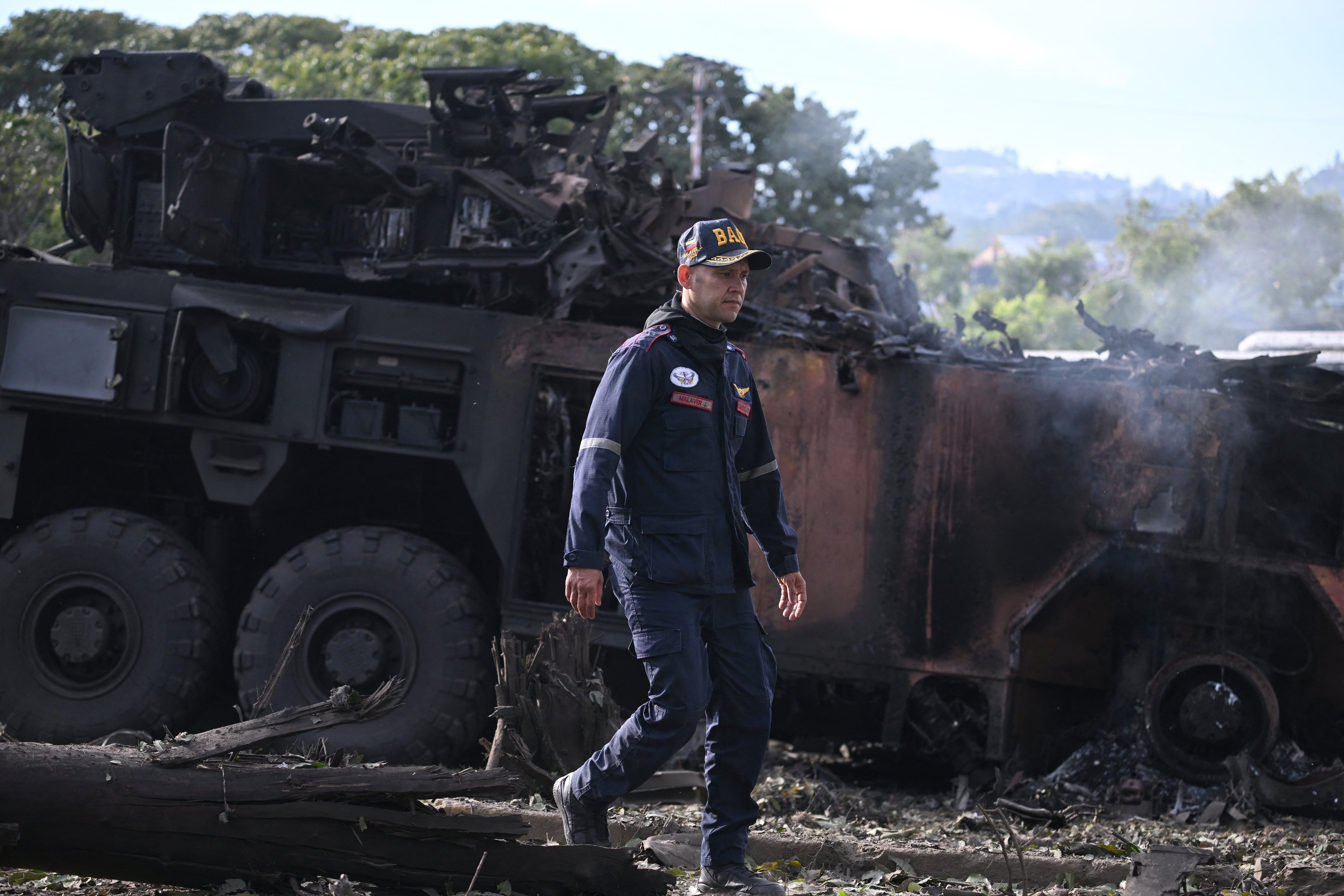 A firefighters passes by a burnt military vehicle at La Carlota air base in Caracas on January 3, 2026, after US forces captured Venezuelan leader Nicolas Maduro after launching a "large scale strike" on the South American country. (Photo by Federico PARRA / AFP)