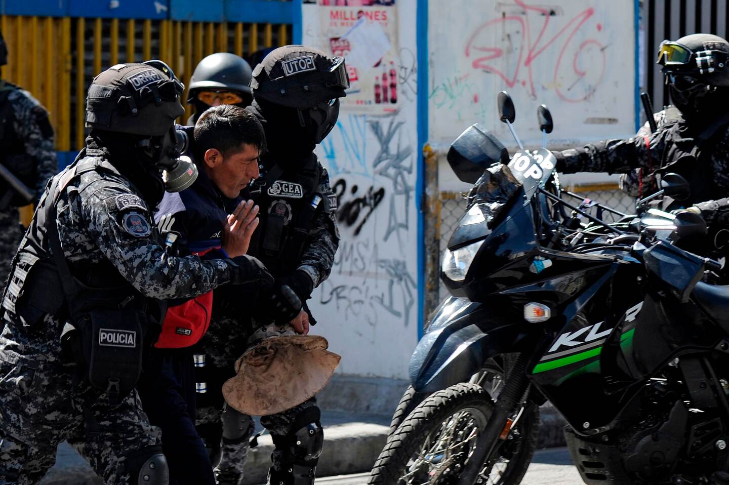 Riot police arrest a man during the funeral procession of eight supporters of Bolivia's ex-President Evo Morales, killed when security forces lifted a siege on a fuel plant, in La Paz on November 21, 2019. - Bolivia's interim President Jeanine Anez asked Congress Wednesday to approve a law that would allow for new elections, after deadly unrest following the resignation of Evo Morales and the disputed October 20 ballot. (Photo by Jorge Bernal / AFP)