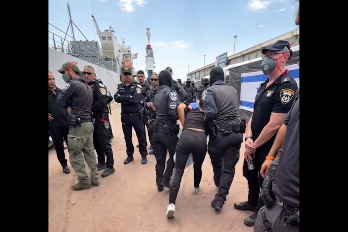 Esta captura tomada del X del ministro de Seguridad, Itamar Ben-Gvir, el 20 de mayo de 2026, muestra a un activista detenido de la flotilla de ayuda con destino a Gaza siendo escoltado por fuerzas de seguridad con las manos atadas detrás de la espalda.
