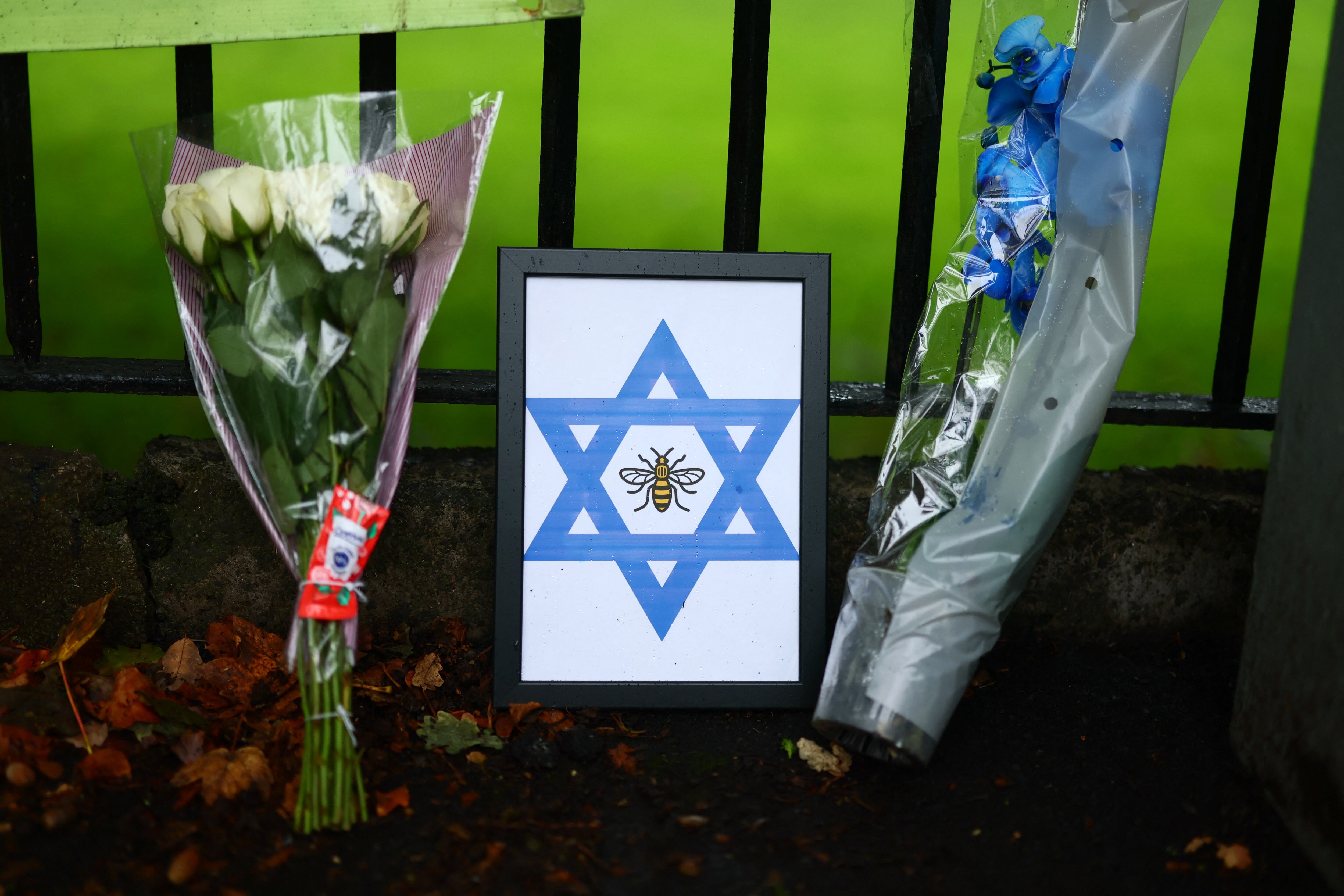 Flores y un homenaje con una abeja y una estrella de David se muestran cerca de la sinagoga de la Congregación Hebrea de Heaton Park en Crumpsall, al norte de Manchester, el 3 de octubre de 2025, tras un ataque ocurrido ayer en la sinagoga.