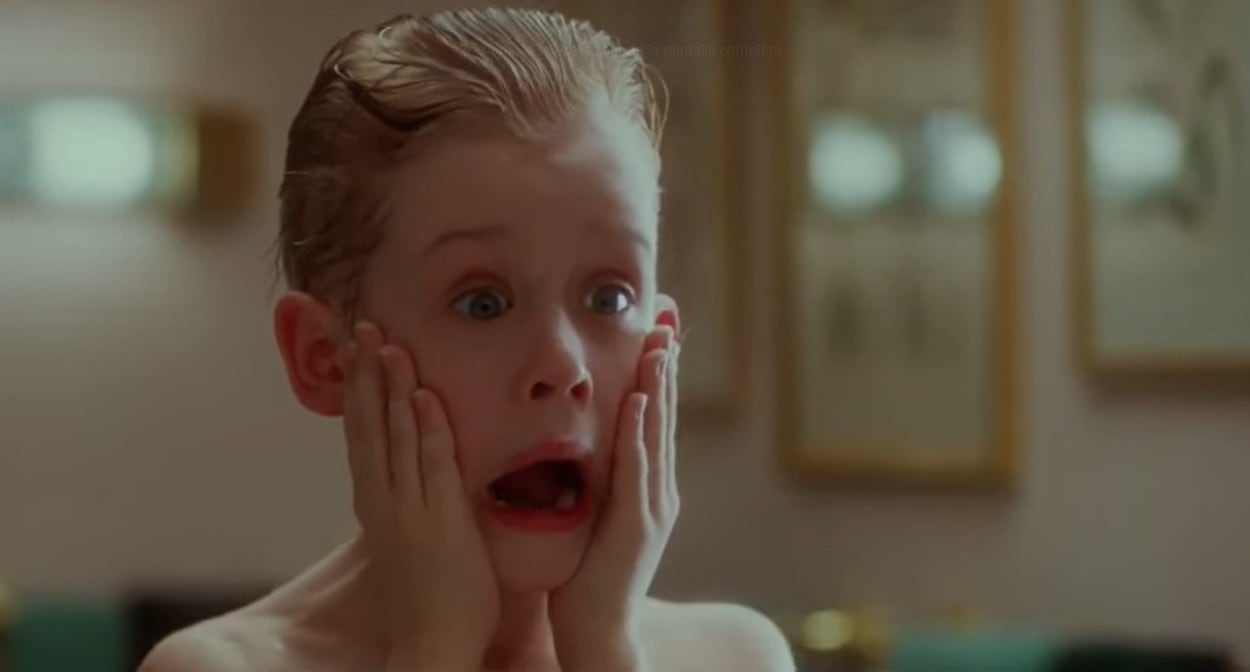 Un niño rubio, con expresión de sorpresa y manos en las mejillas, en una escena clásica de la película Mi Pobre Angelito (1990), destacada como un símbolo de la cultura pop navideña.