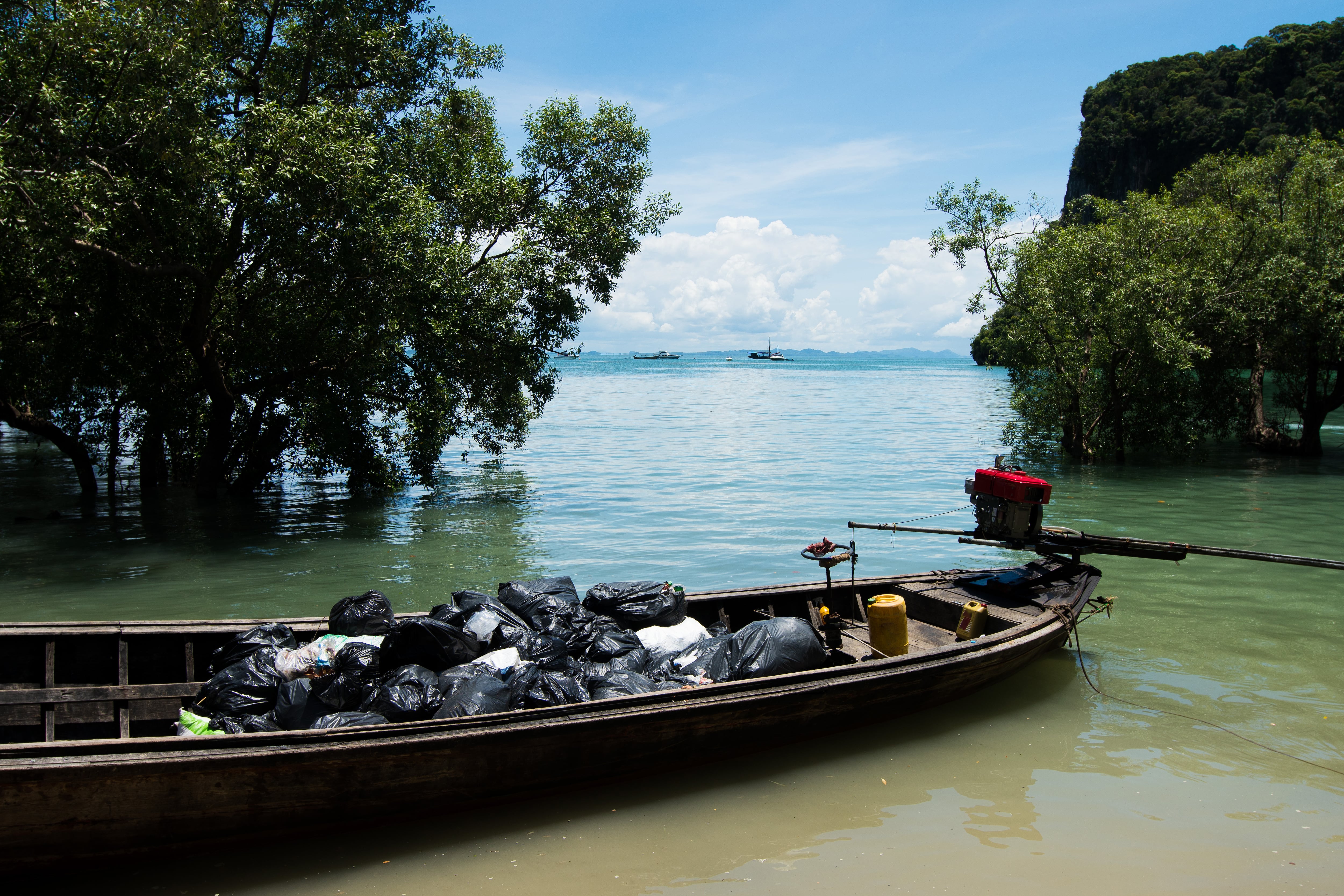 Un bote lleno de bolsas de basura a la orilla del mar