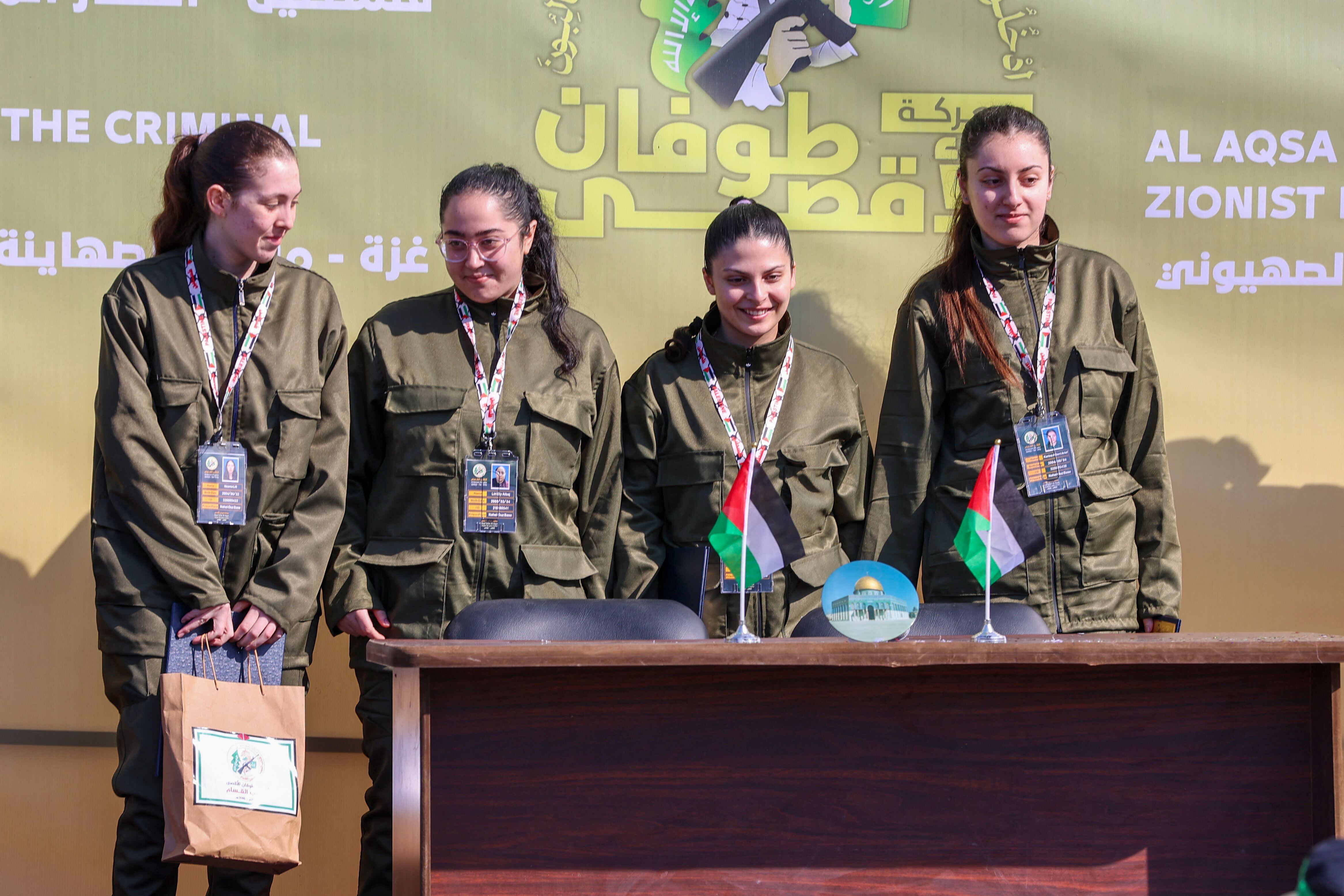 Cuatro mujeres rehenes israelíes liberadas por Hamás, de pie en un escenario, con combatientes armados al fondo, antes de ser entregadas a la Cruz Roja en Ciudad de Gaza.