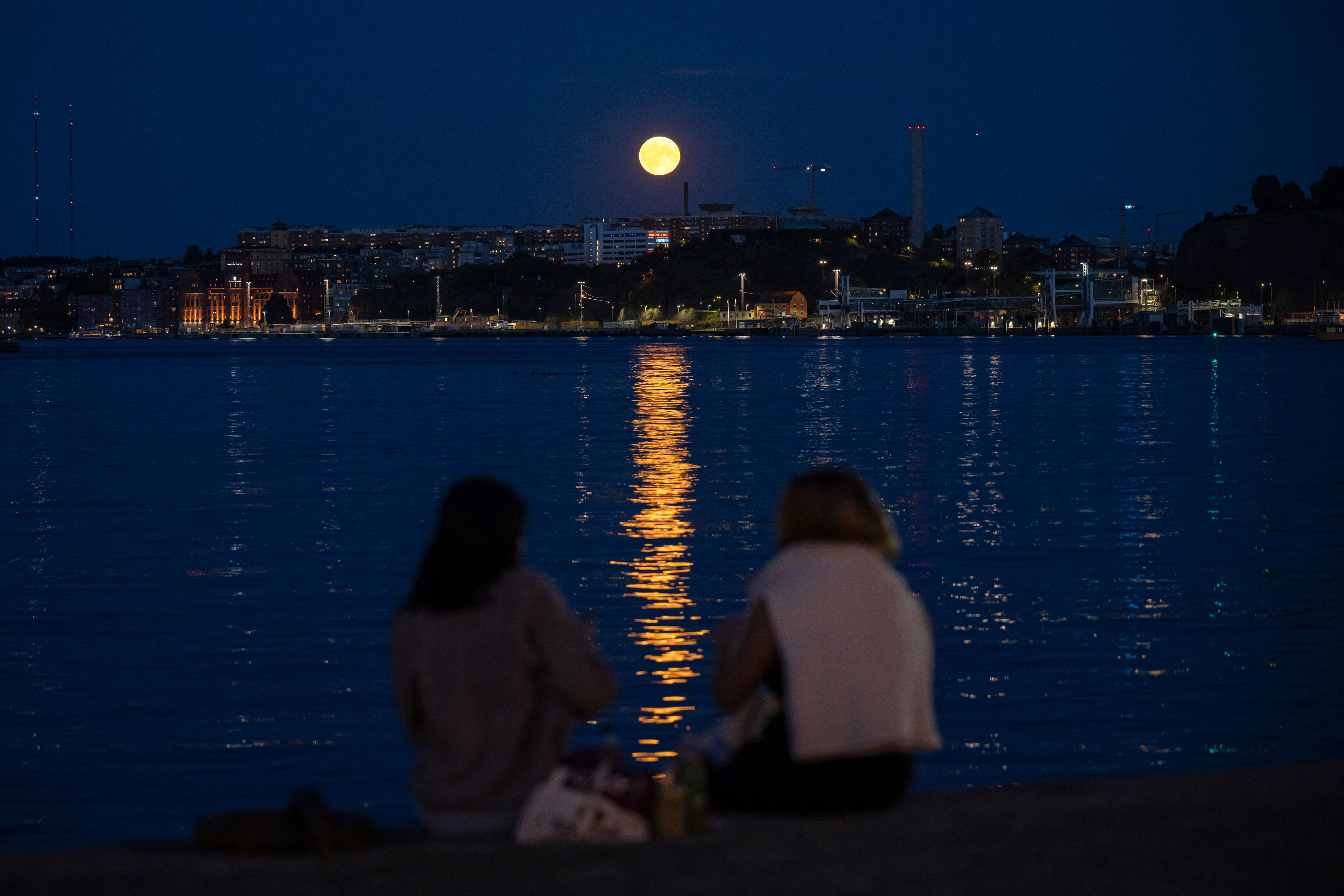 People watch as a Super Blue Moon rises behind Nacka, in Stockholm, on August 19, 2024. (Photo by Jonathan NACKSTRAND / AFP)