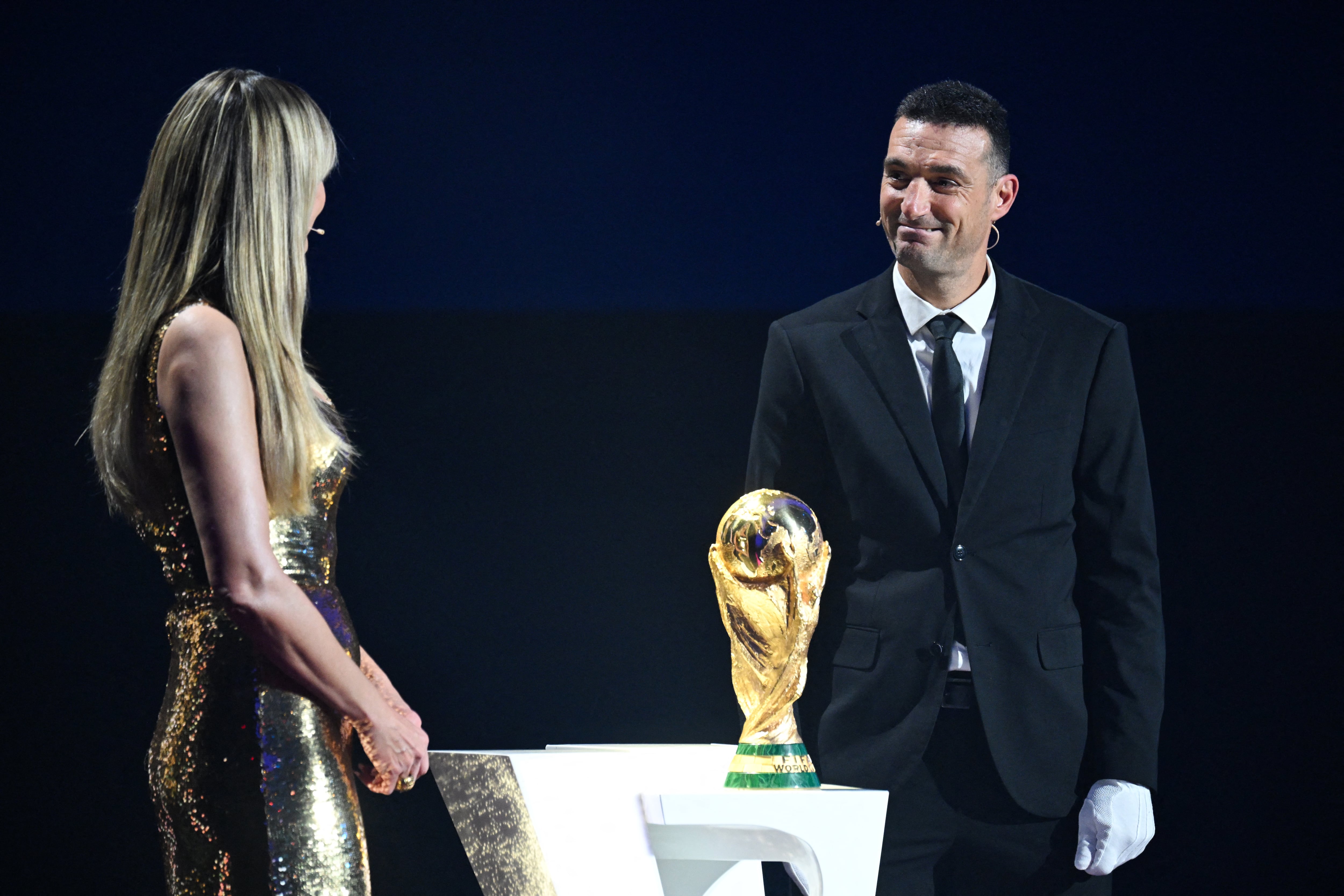El entrenador argentino Lionel Scaloni se encargó de transportar el trofeo de la Copa del Mundo durante el sorteo. Aquí conversa con la modelo Heidi Klum, una de las presentadoras.