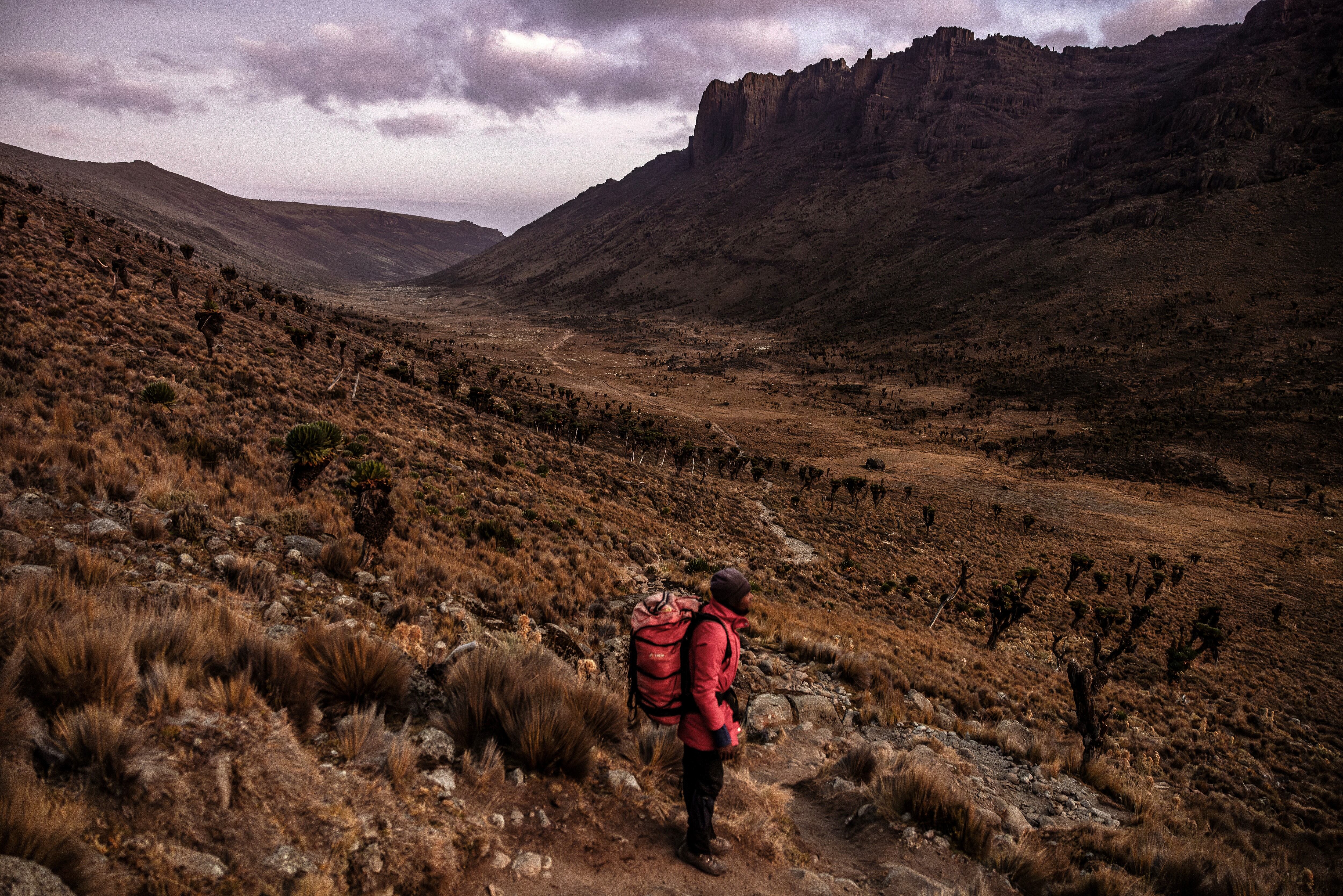 Professional mountaineer guide and porter Godfrey Mwangi, 28, takes a short rest overlooking Mackinder's Valley at dawn, inside Mount Kenya National Park, on March 8, 2025. Mount Kenya, Africa's second-highest peak, is home to rapidly shrinking glaciers that are vital for nearby ecosystems and c