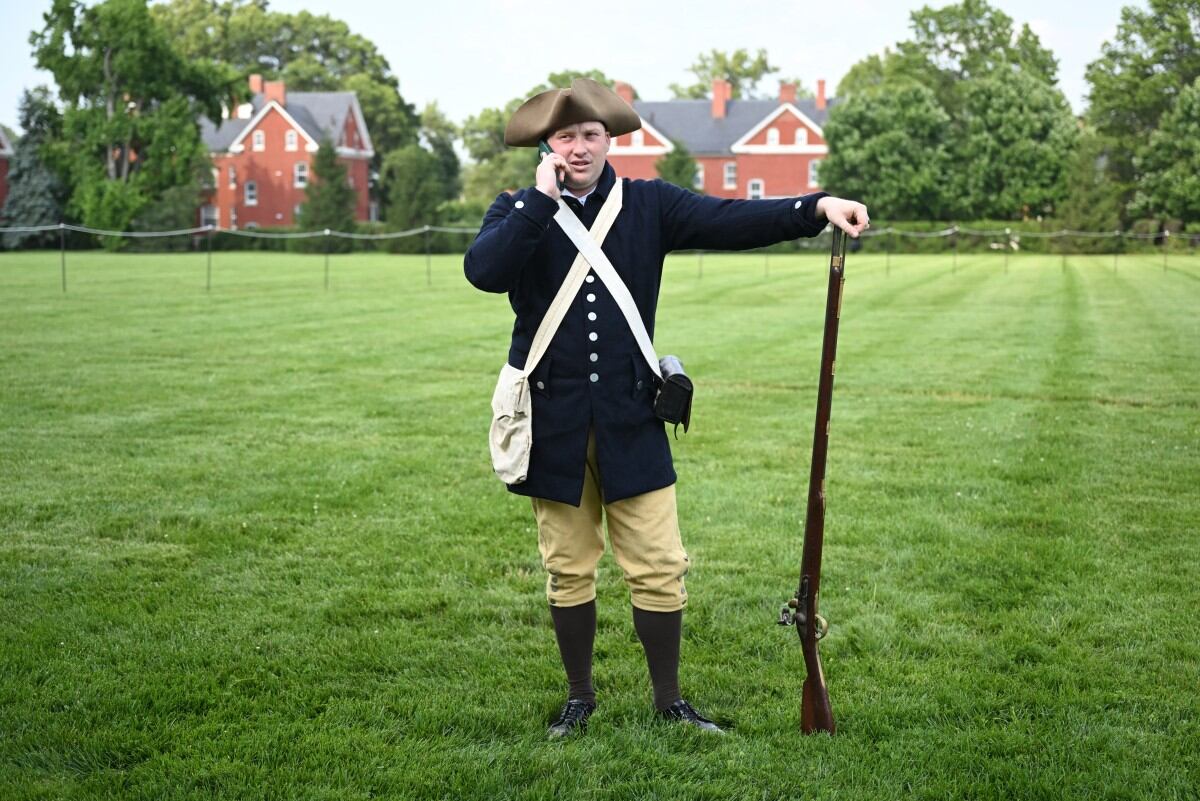 El especialista Michol Pavlik, vestido como un miembro de la milicia colonial, habla por teléfono celular antes del inicio del evento Twilight Tattoo del Ejército de los Estados Unidos en la Base Conjunta Myer-Henderson Hall, en Arlington, Virginia, el 11 de junio de 2025. El Twilight Tattoo del Ejército de EE. UU. es un evento militar que presenta a soldados de las unidades ceremoniales del Distrito Militar de Washington. Un desfile militar y una celebración por el 250.º aniversario del Ejército de EE. UU. se llevarán a cabo en Washington, D.C., el 14 de junio, fecha que también coincide con el cumpleaños número 78 del presidente Donald Trump. (Foto de ANDREW CABALLERO-REYNOLDS / AFP)