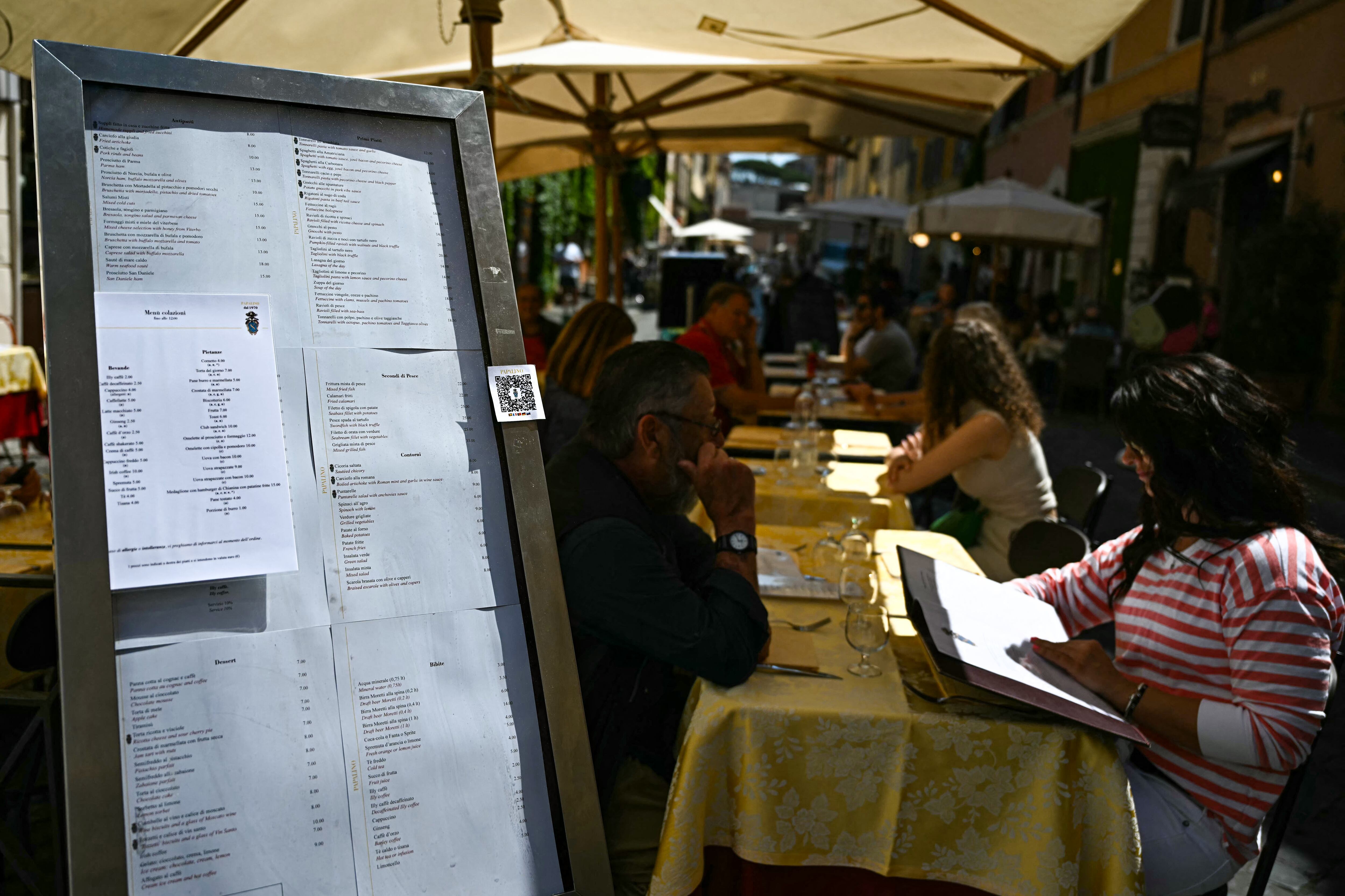 Clientes se sientan en la terraza de un restaurante en la calle Borgo Pio, en Roma, a la espera del cónclave 2025.