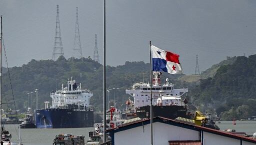 Buques en tránsito por el canal de Panamá con la bandera de Panamá ondeando en primer plano, símbolo de soberanía nacional.