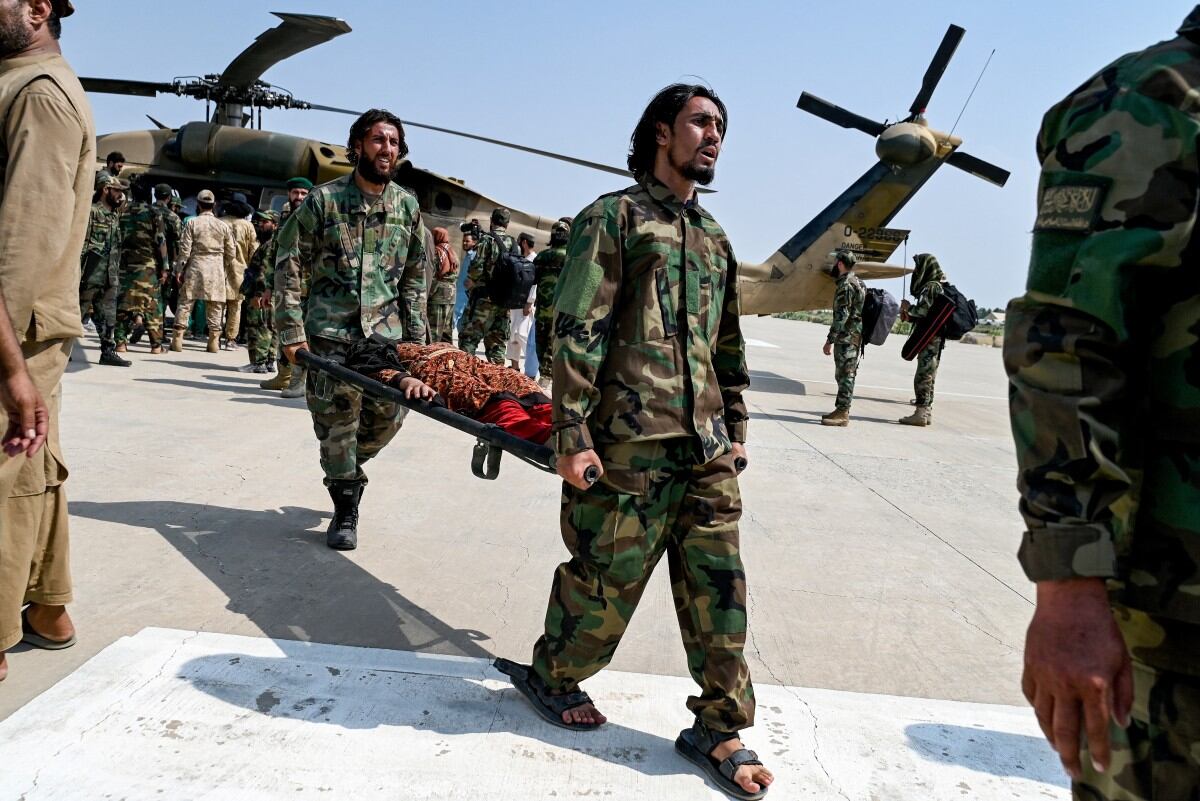 Taliban security personnel carry an earthquake victim evacuated by a military helicopter from the Nurgal district of Kunar province, after her arrival for medical assistance in Jalalabad on September 1, 2025.