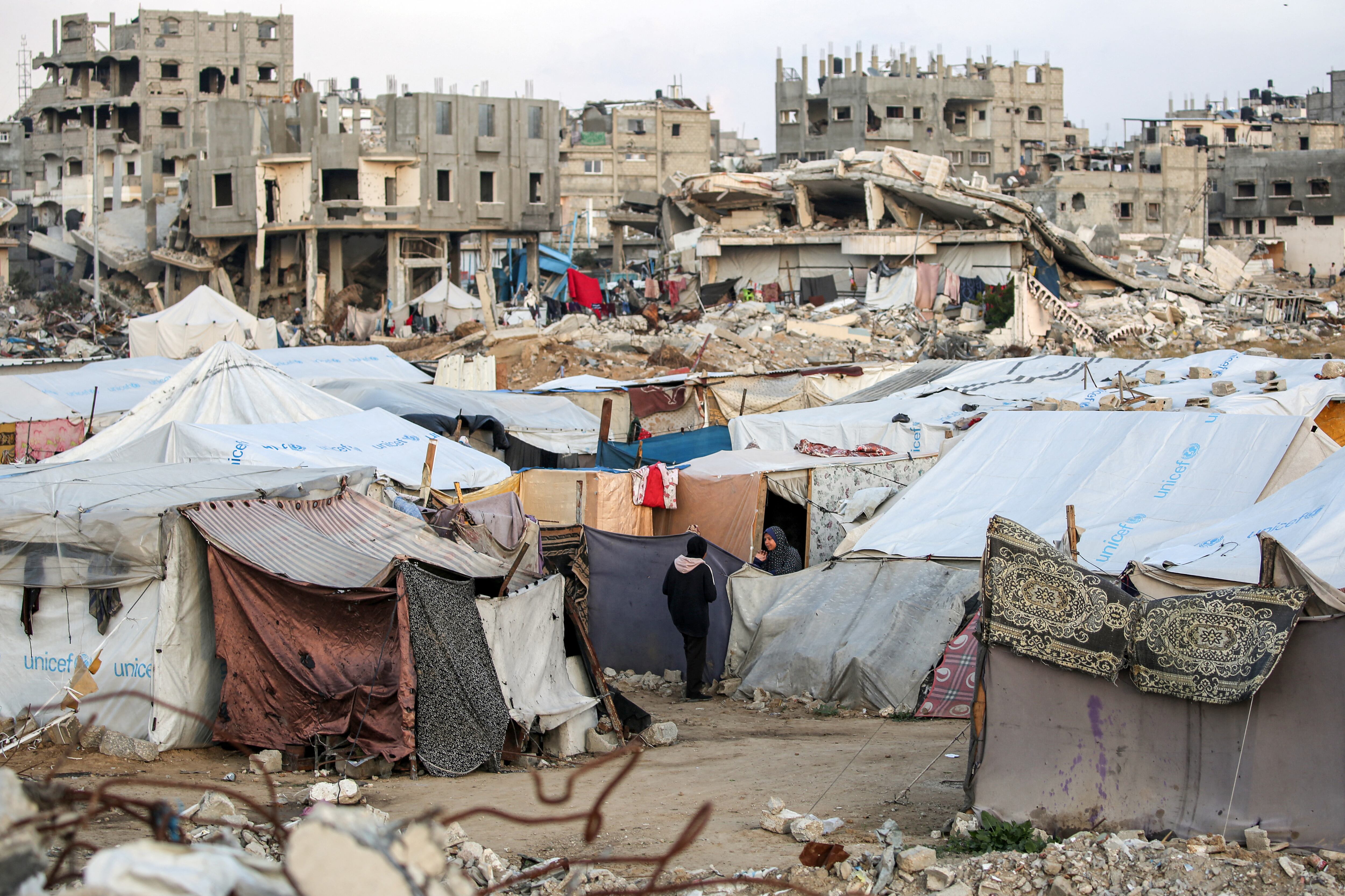 Una mujer habla con una niña fuera de una tienda de campaña en un campamento para desplazados por el conflicto en Bureij, en el centro de la Franja de Gaza.