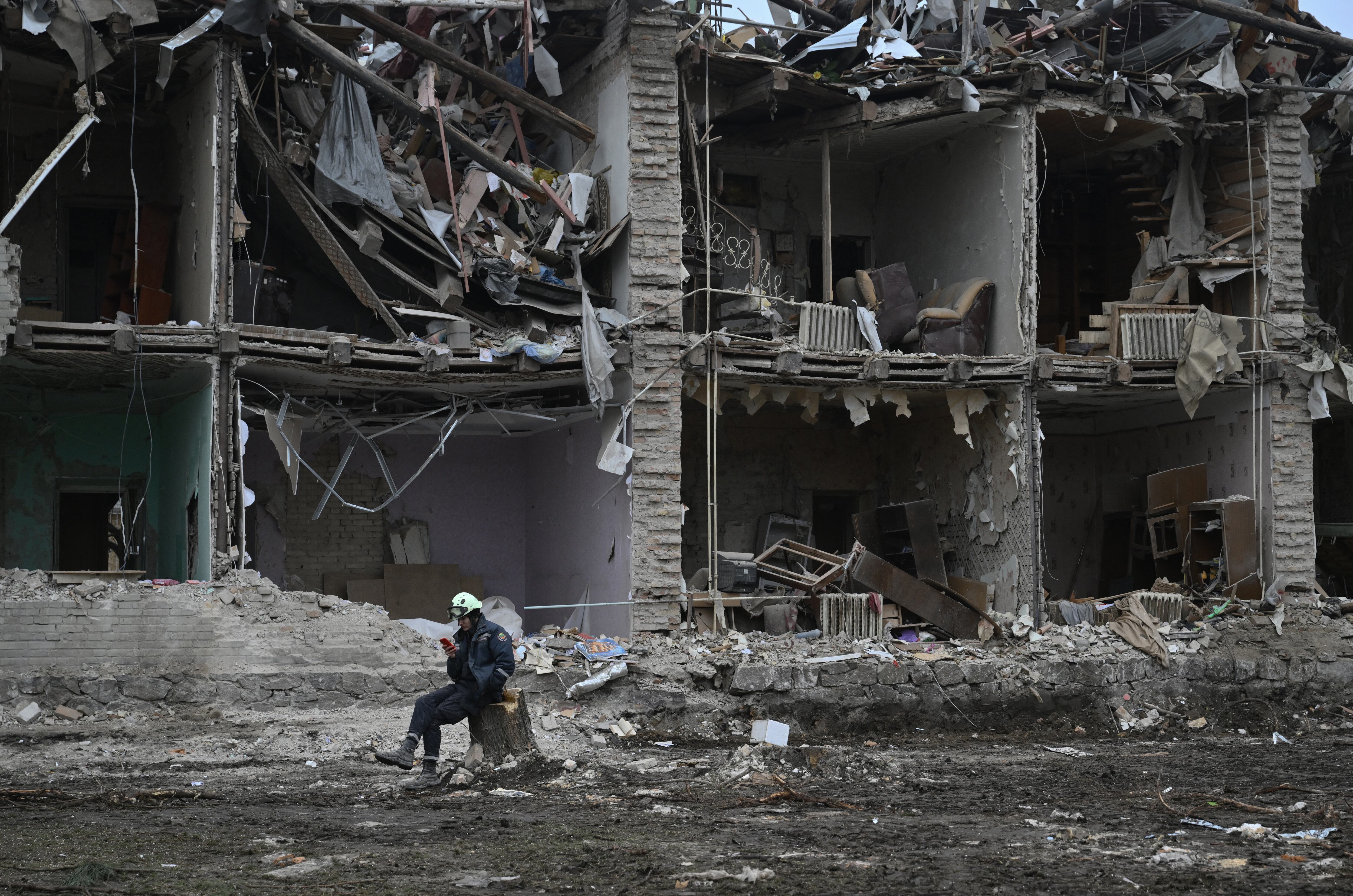 A rescuer sits next to a residential building, heavily damaged few days earlier following a Russian strike in the Zaporizhzhia on January 26, 2025, amid the Russian invasion of Ukraine. (Photo by Genya SAVILOV / AFP)
