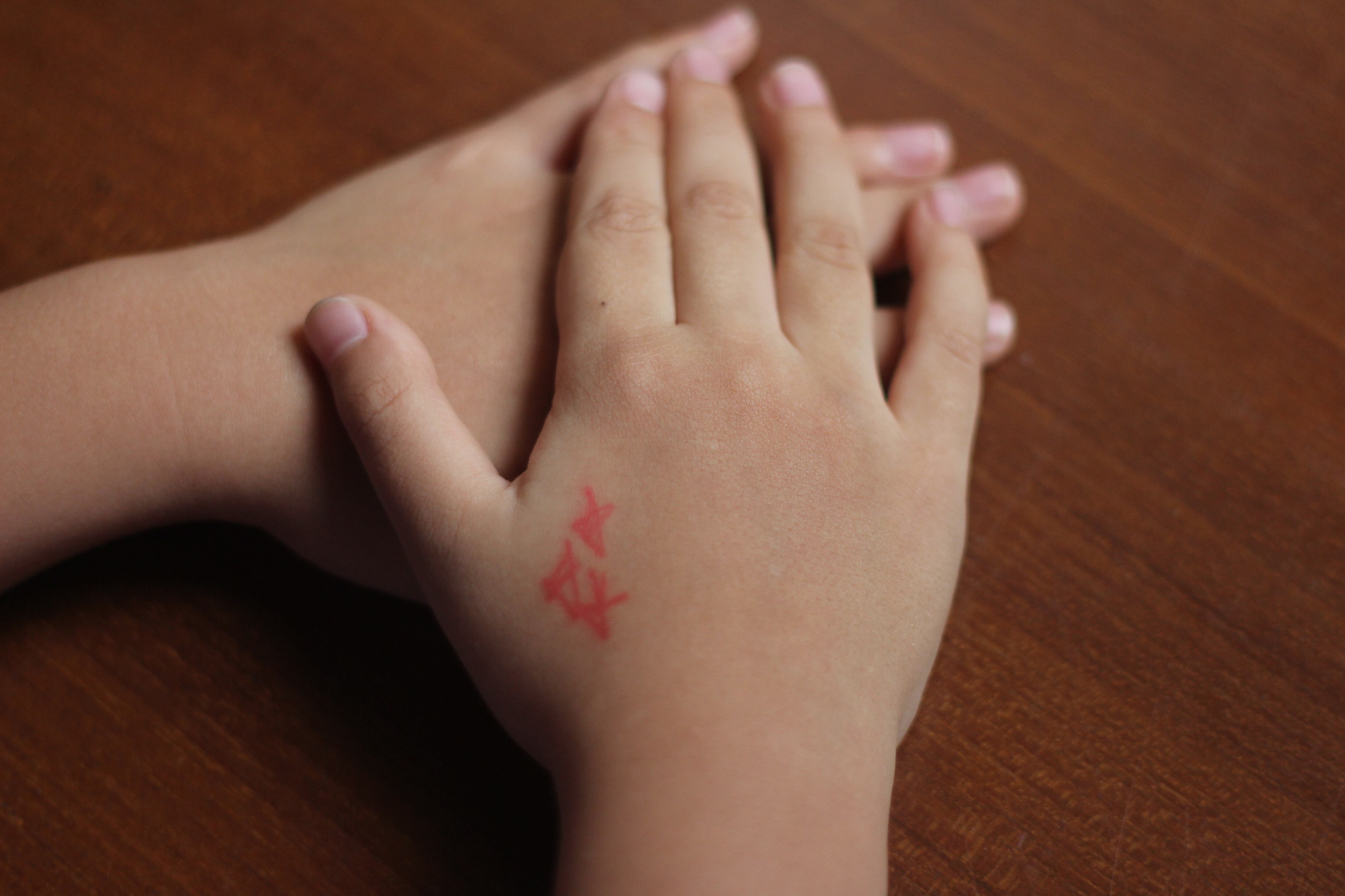 Manos de niño o niña con pequeñas estrellas rojas, primer plano de manos de menor de edad