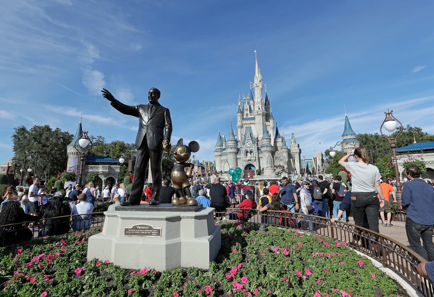 Visitantes cerca de la estatua de Walt Disney y Mickey Mouse frente al Castillo de Cenicienta en Magic Kingdom, en California.