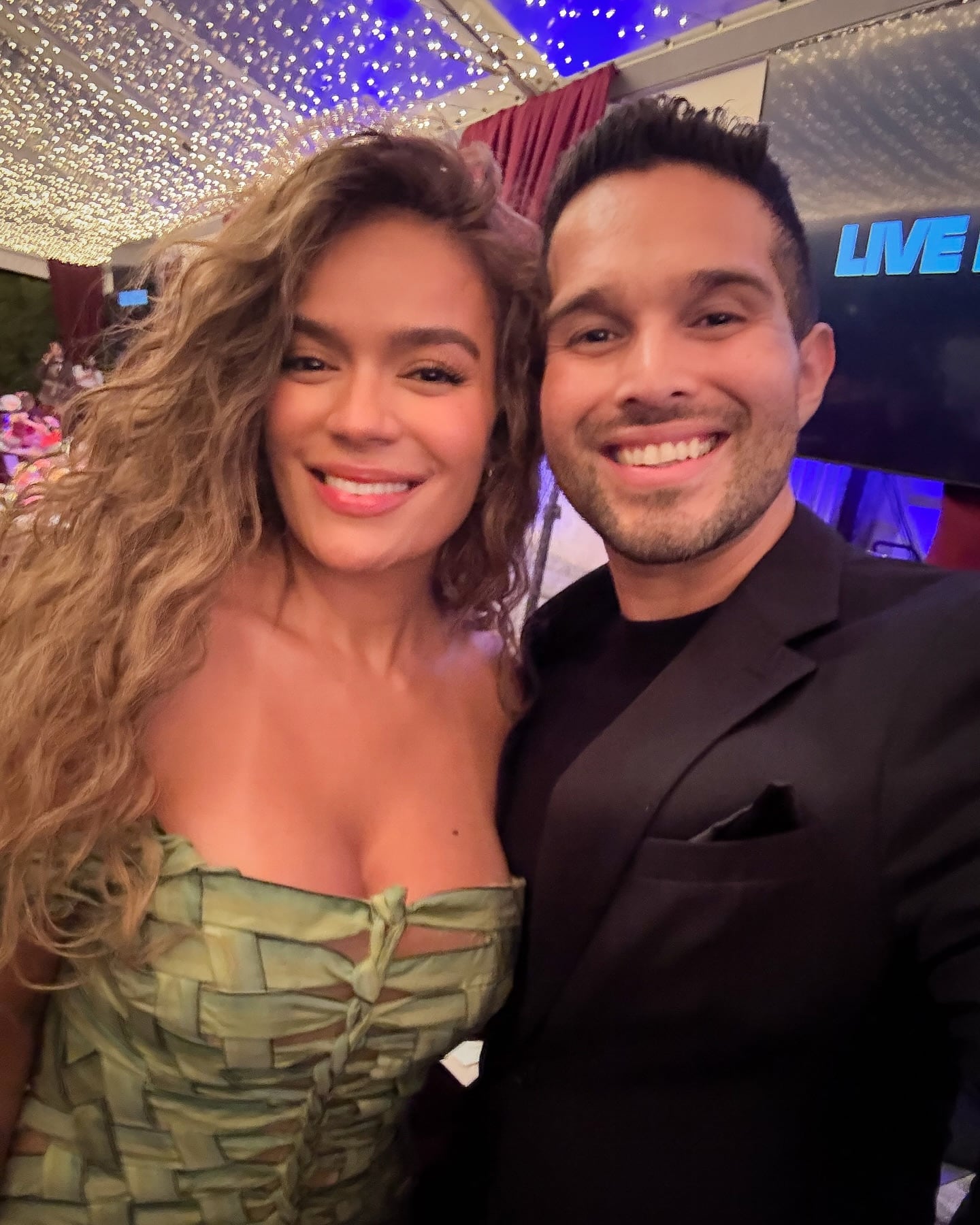 Eduardo Aguirre junto a Karol G en primer plano.