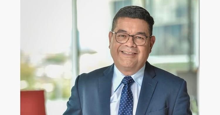 El periodista pensionado Marcelo Castro usando un traje y corbata azul y camisa blanca. Sonríe hacia la cámara.